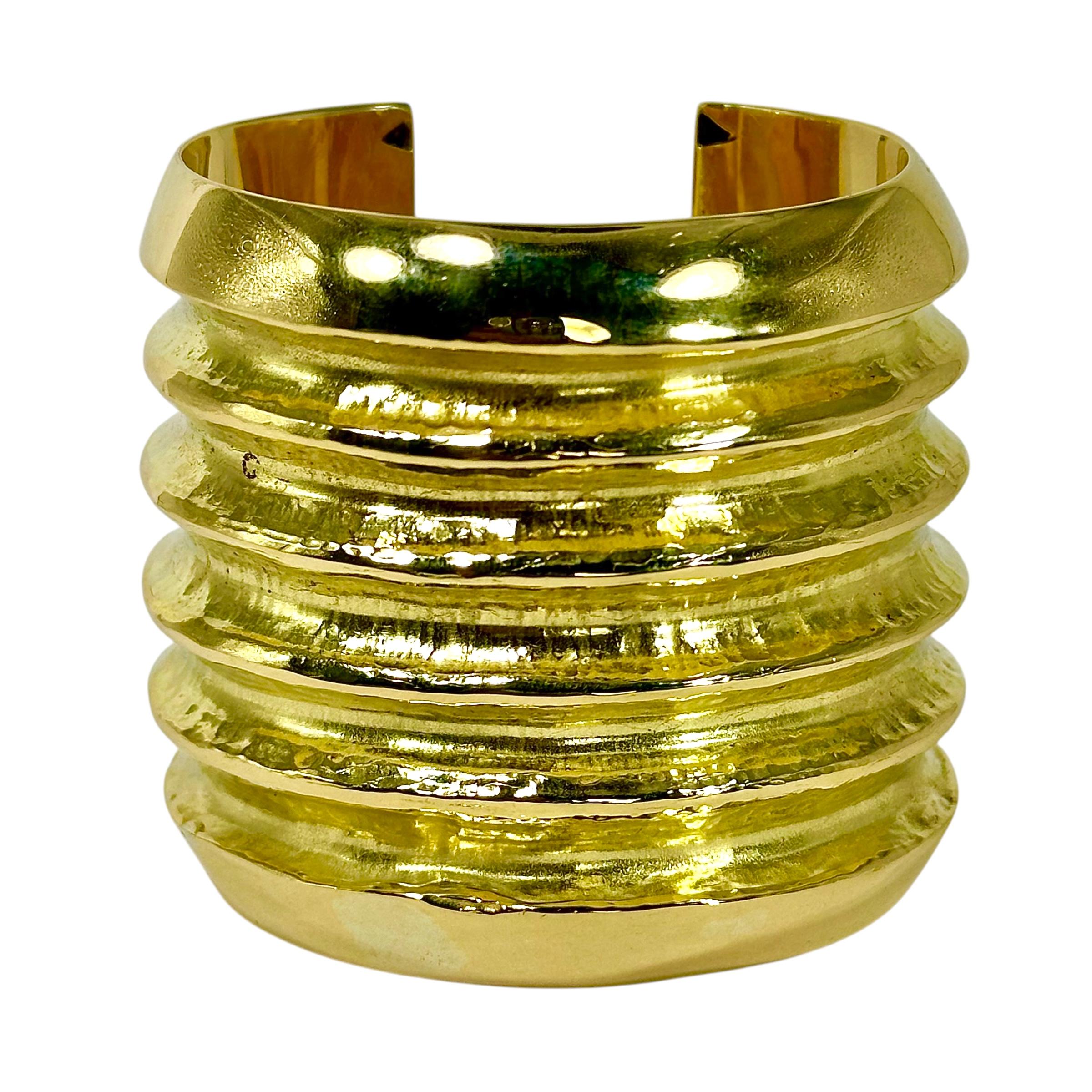 This remarkable vintage 18k yellow gold cuff bracelet measures an astonishing 2 3/8 inches wide. With high polish, wide beveled edges contrasting the deep, hammered channels, its design is simple yet visibly palpable. The two different textures and