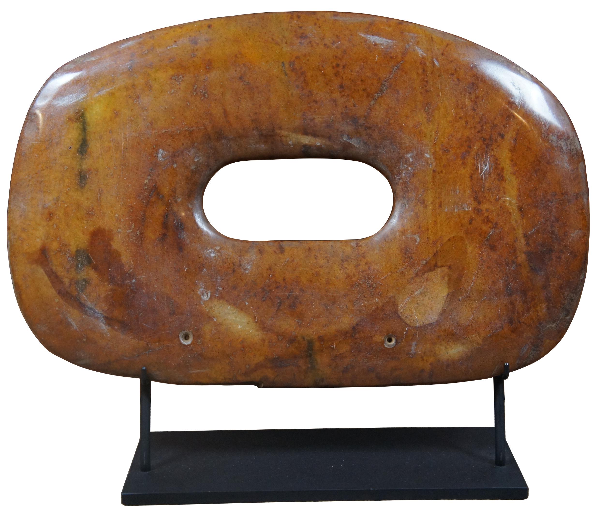 Paire de bi-disques en pierre sculptée orange/brune. Le disque bi ou pi est un disque plat avec un trou circulaire au centre. Les disques remontent à l'époque néolithique (5 000-2 000 ans avant J.-C.). Les archéologues supposent que la forme ronde