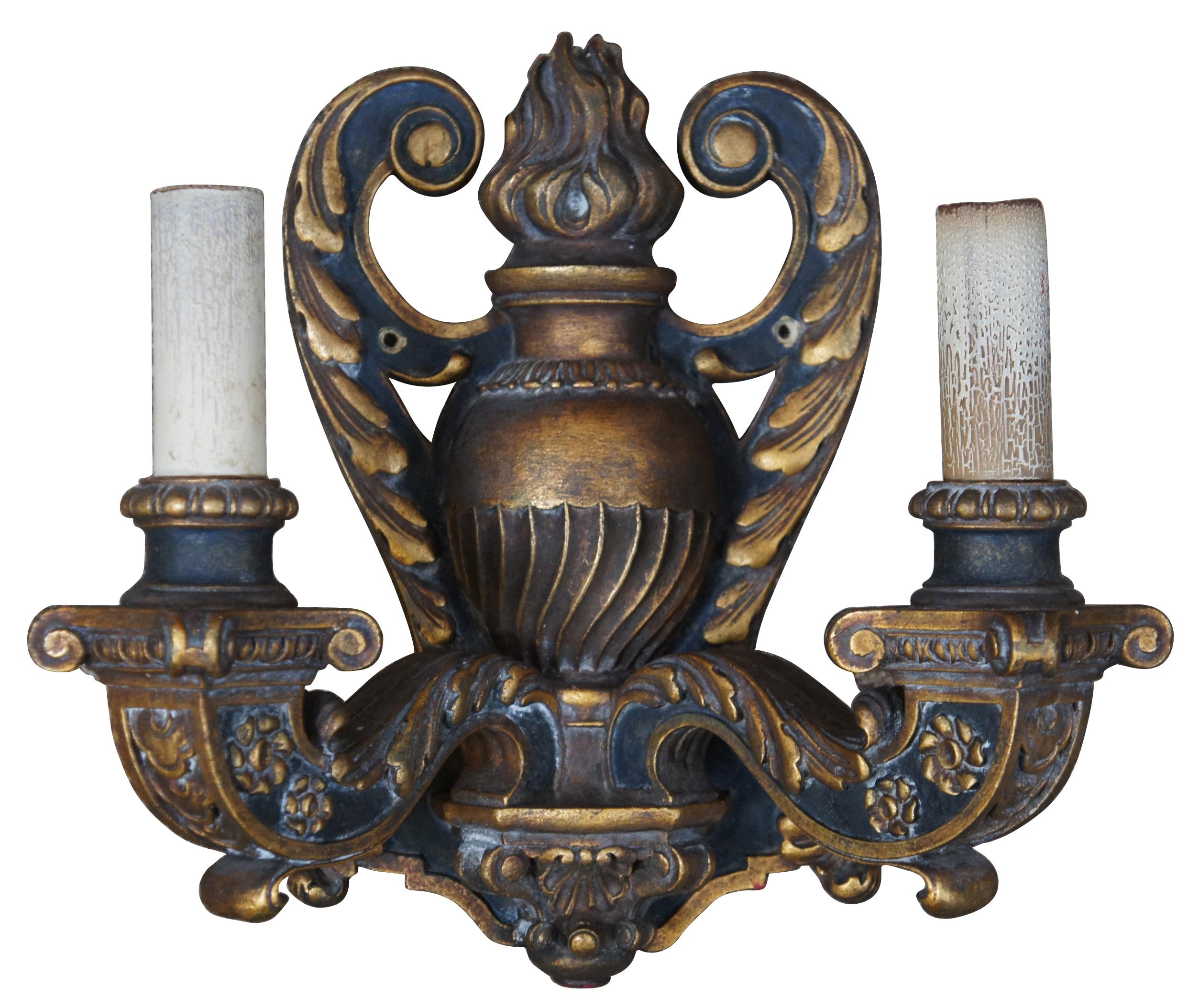 Circa 1910 Baroque Revival electric wall sconces in the shape of black and gold (Dore) wall mounted candlesticks decorated with leaves, flowers and a flaming urn.
 