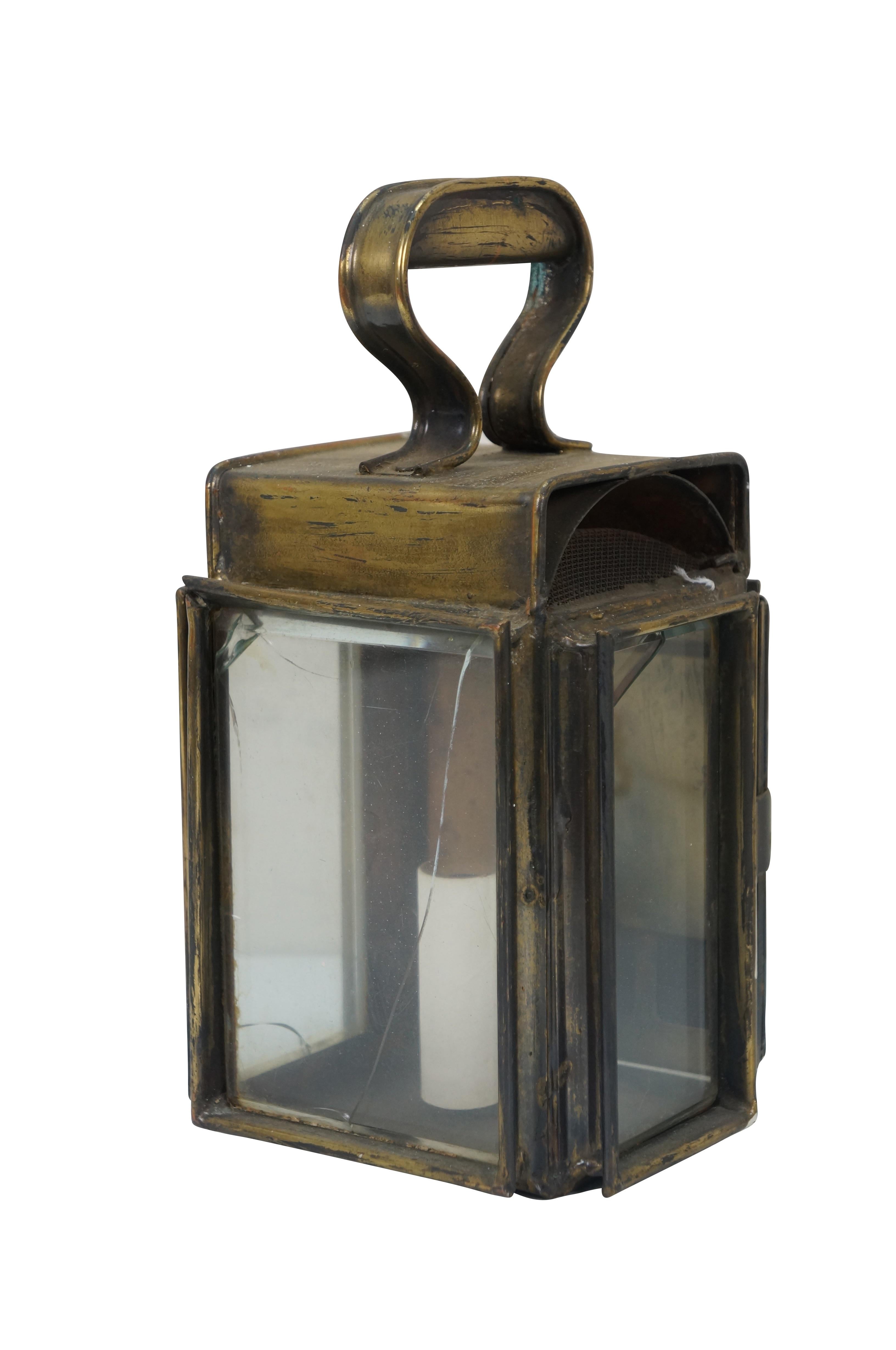 Pair of electric wall sconces made from converting antique brass canal / railway signal / carriage lanterns - rectangular form with glass on three sides, vented top and fixed handle. Opens from back to a faux candlestick socket. Hard