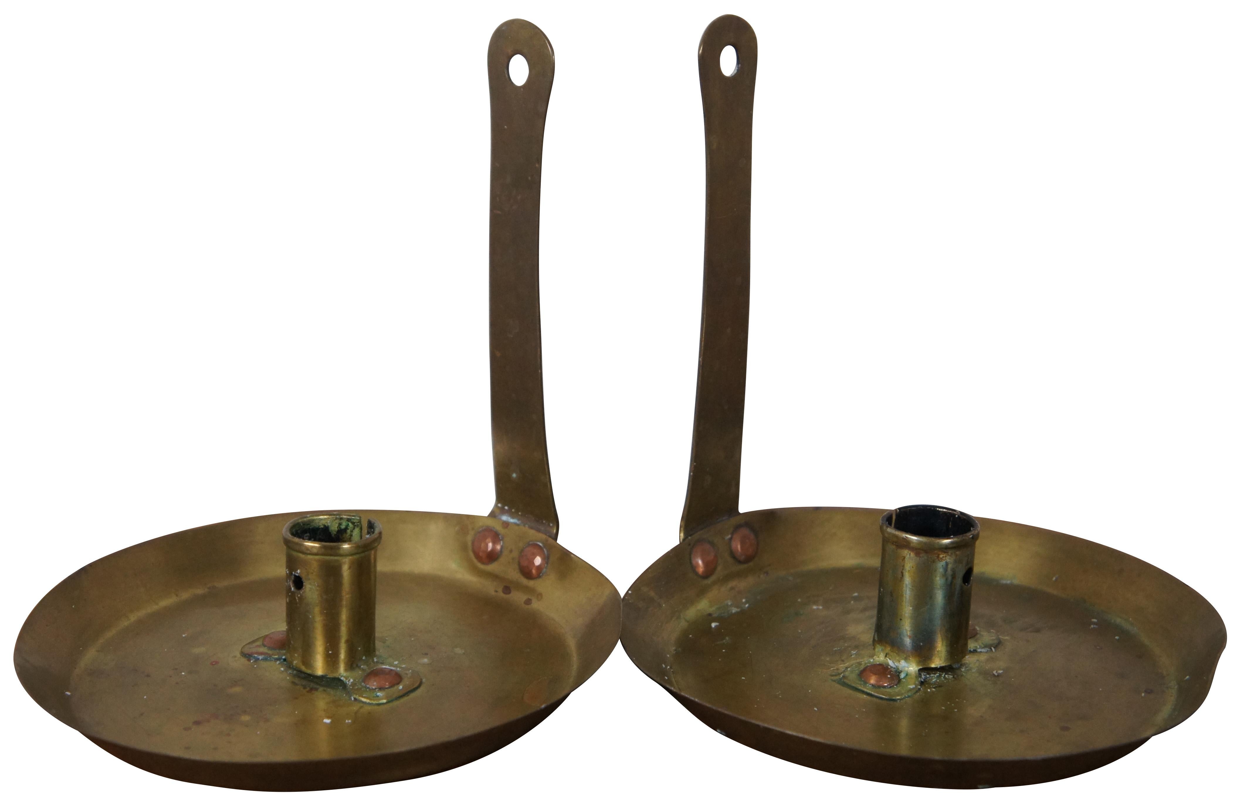 Pair of antique primitive brass chamber stick candle holders in the manner of a frying pan with tall straight handle that could be used to hang the holders as wall sconces.