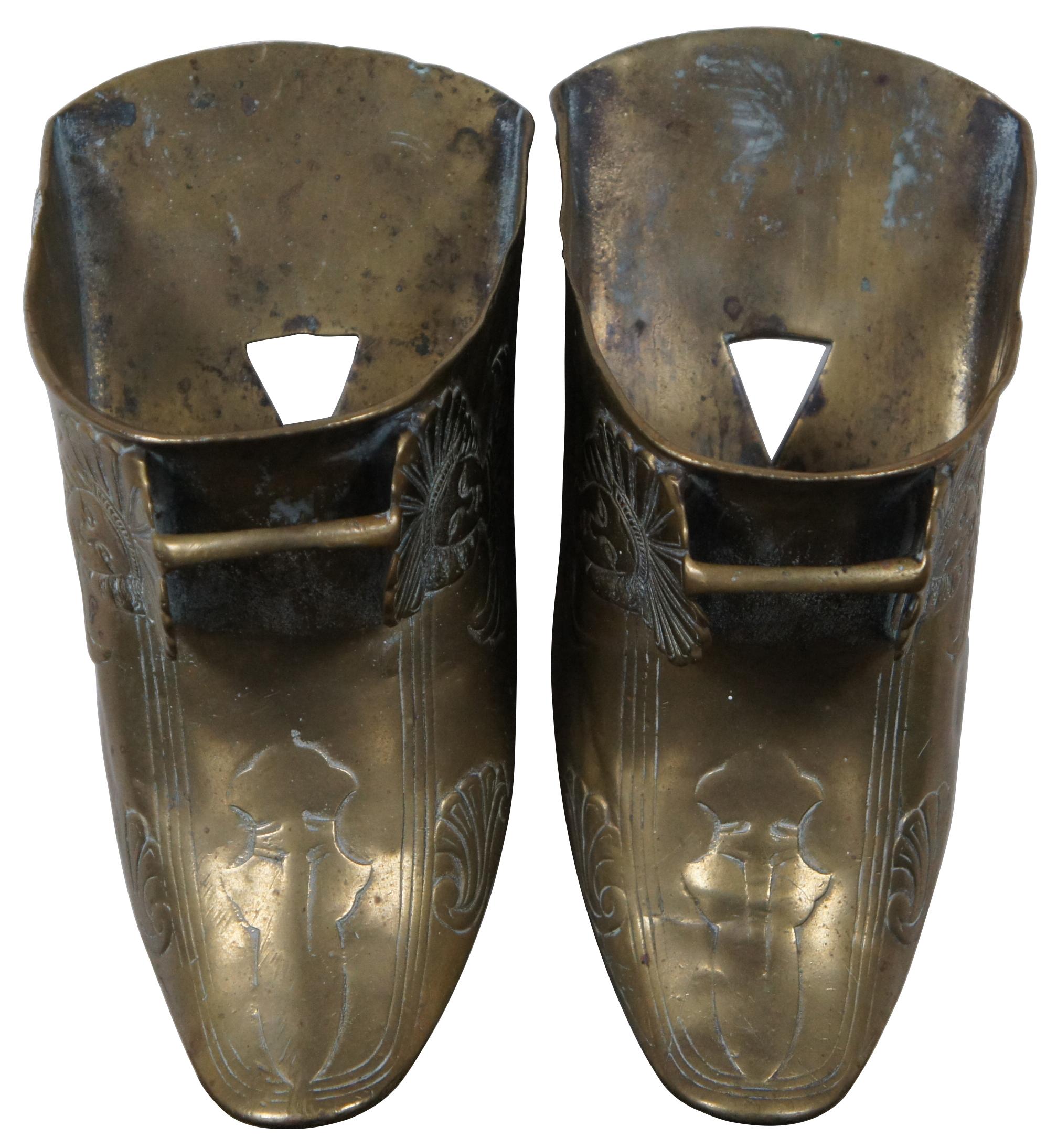 Pair of antique brass horse stirrups in the style of the Spanish Conquistadors, decorated with a European re-imagining of an Aztec or Mayan figure in a feathered robe and headdress.
       