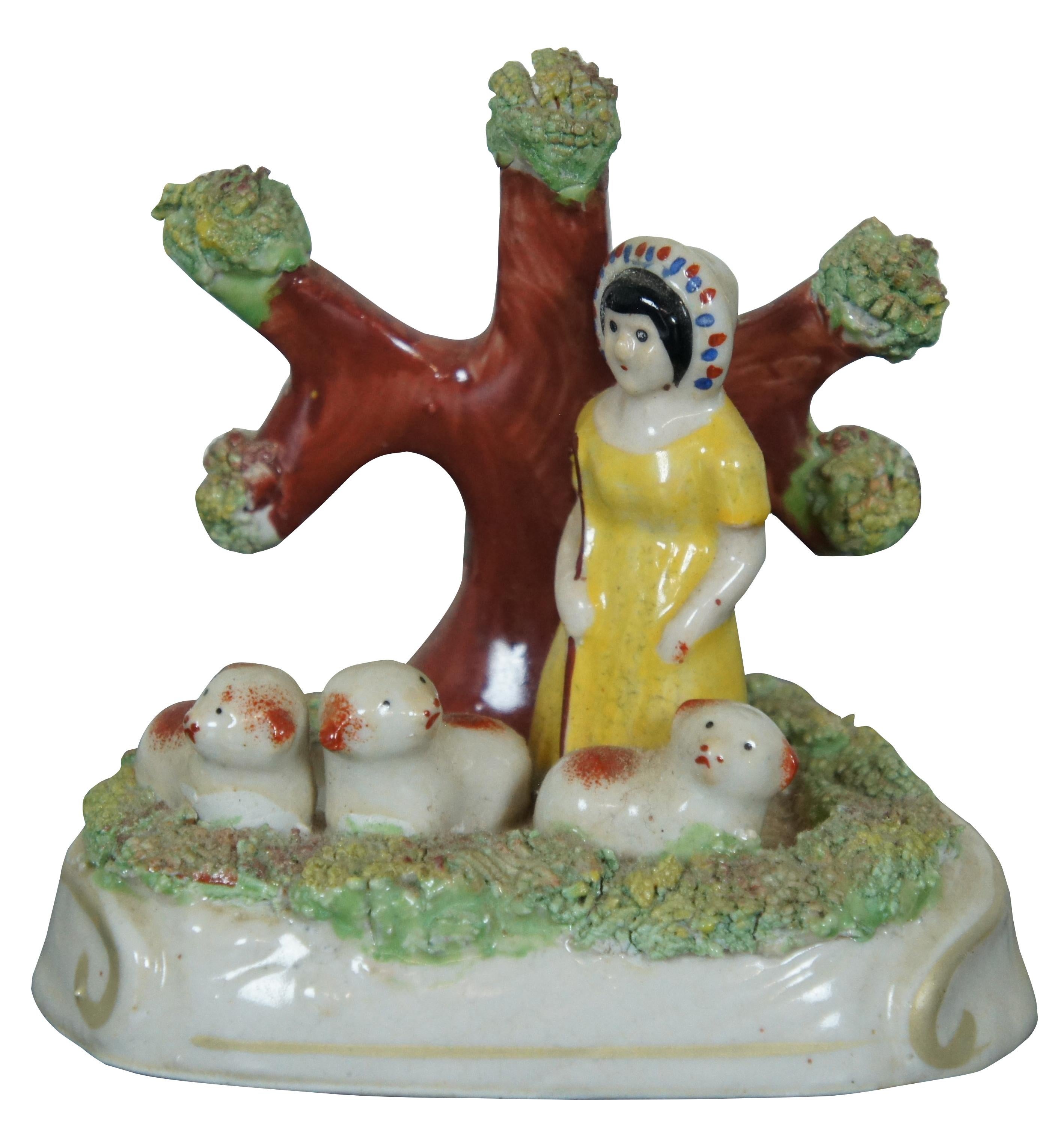 Pair of antique early Staffordshire pearlware bocage figures, a shepherd and a shepherdess each standing in front of a tree with three red and white sheep / lambs. Each piece uses shredded clay to simulate grass and foliage. Attributed to the James