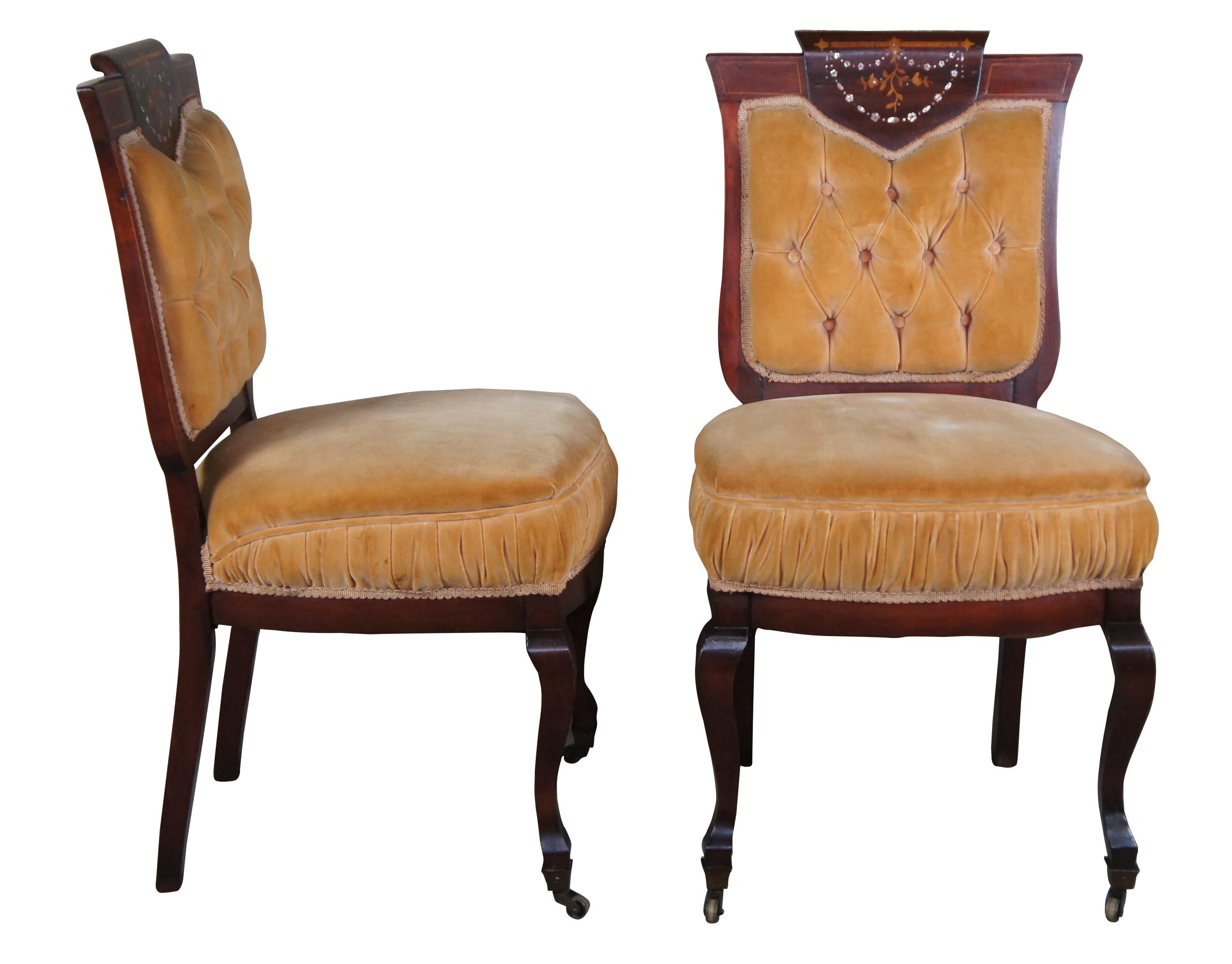 Gorgeous pair of early 20th century English Edwardian side chairs. Made from Mahogany with walnut inlaid floral marquetry and Mother of Pearl Inlay. Chair backs are shield shaped with banding and tufted upholstery. Legs are square tapered leading to