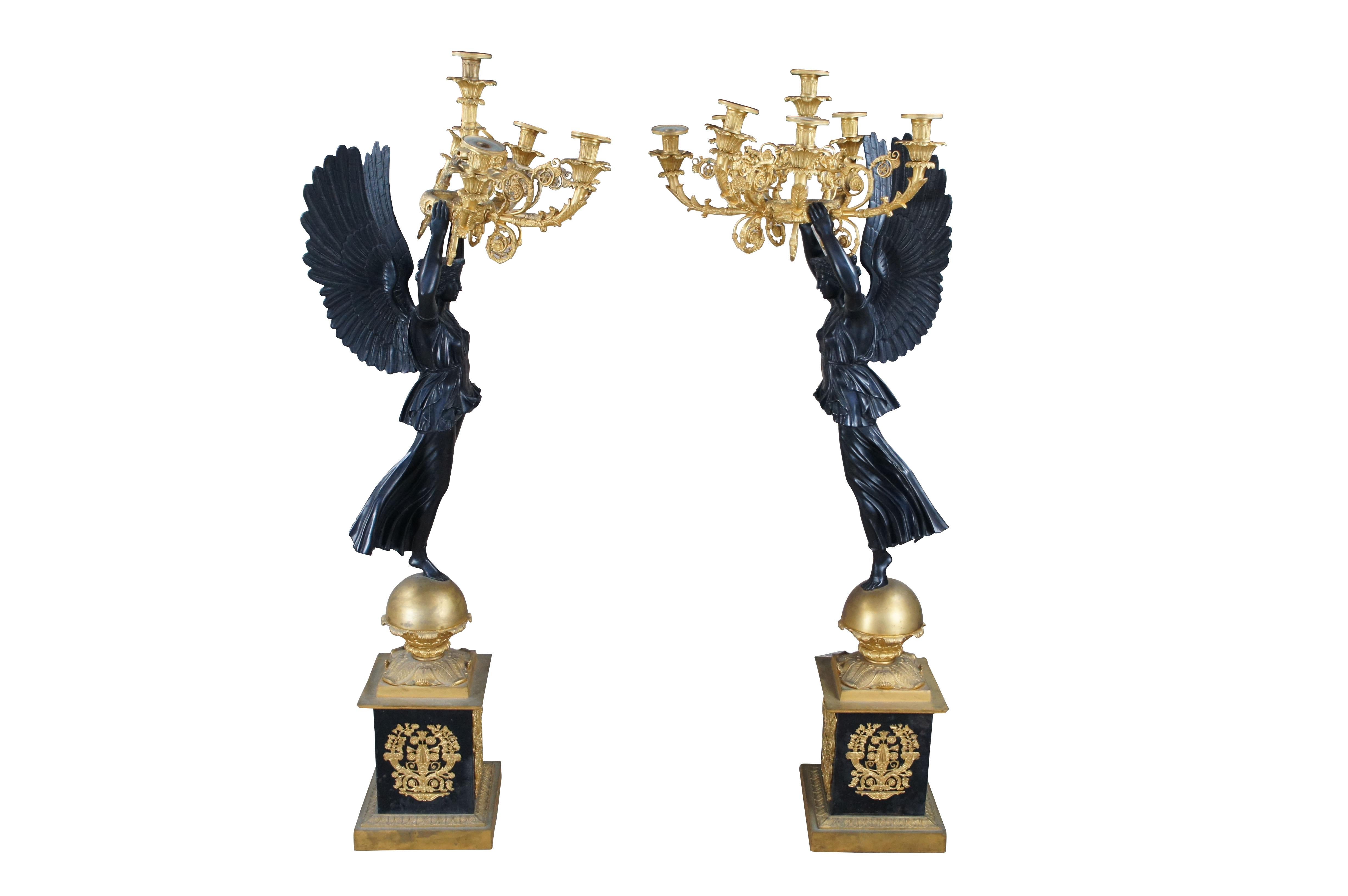 Monumental pair of large figural French gilt bronze candelabras possibly executed by Pierre Philippe Thomire, circa 19th century. Each candelabra is supported by a Nike-form standing on one leg over an orb stepped plinth base with ornate applied