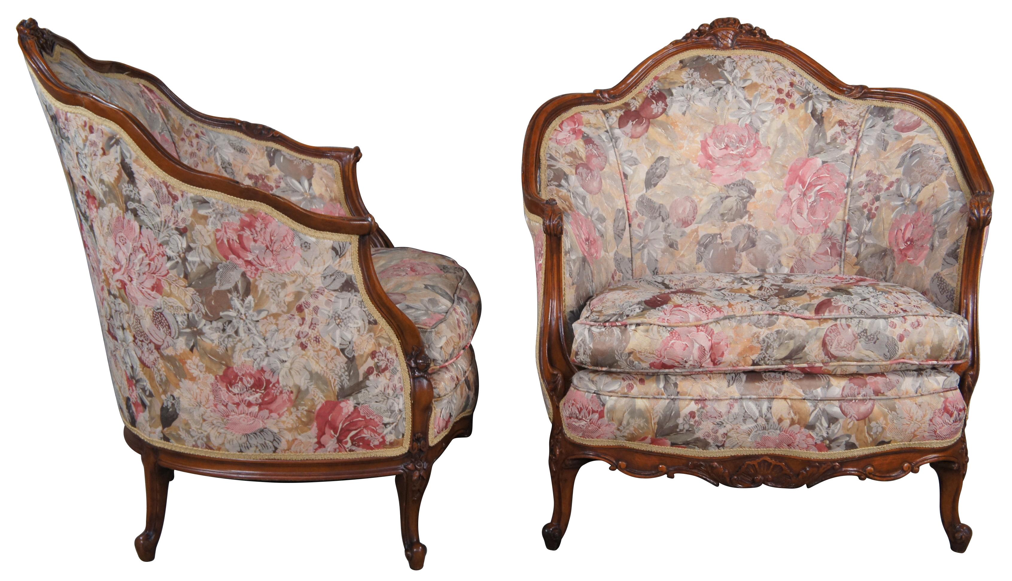 An incredible pair of antique French His & Hers bergere club arm chairs. Made from walnut with a scalloped barrel back design, carved with medallions, foliate, shells, cornucopia and acanthus. Upholstered in a pastel like fabric with cording and