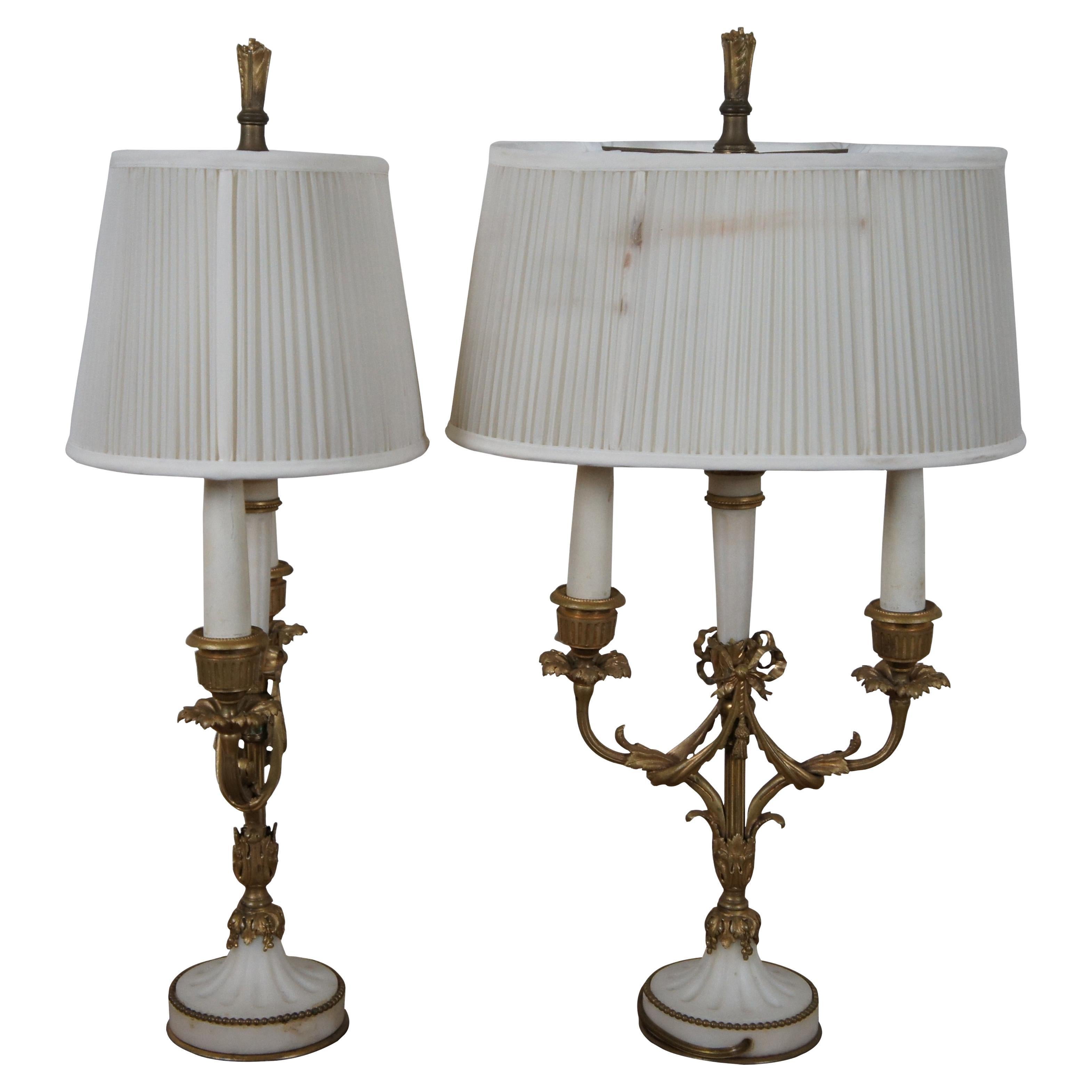 Pair of antique French neoclassical bouillotte two light table lamps featuring white Alabaster stone accents with intricate fluted gilt bronze design. The body and arms feature an acanthus floral and ribbon motif, with faux wood candle holders /