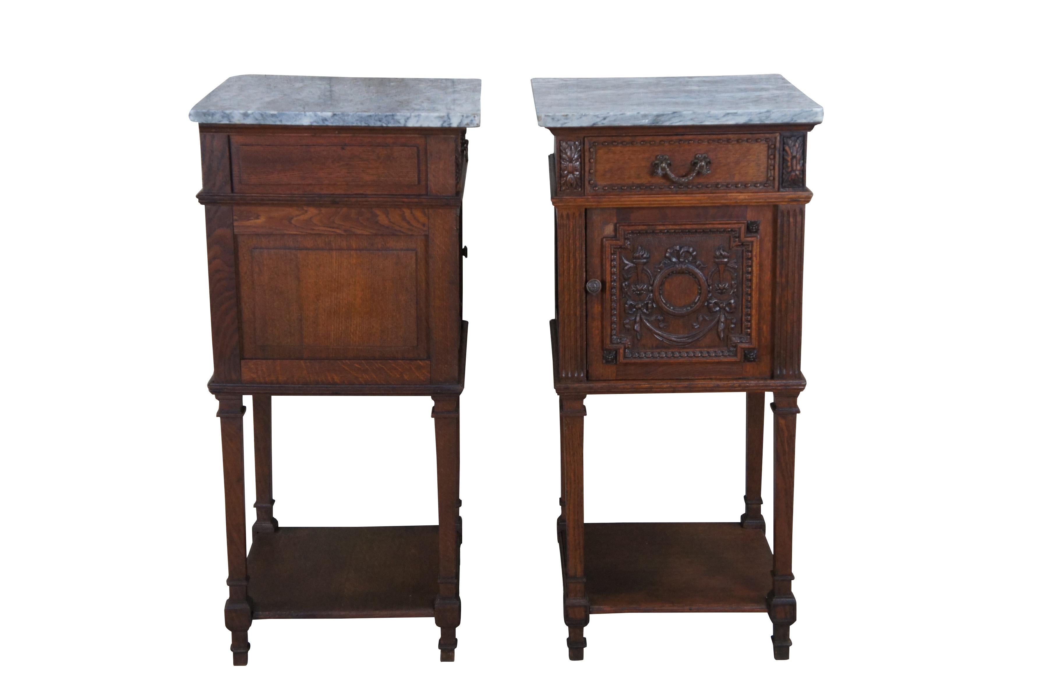 Two antique French tobacco humidor / smoke stands.  Made of quartersawn oak featuring a two tiered design with marble top and paneled Neoclassical torchiere / ribbon theme door. 

Dimensions
15.75