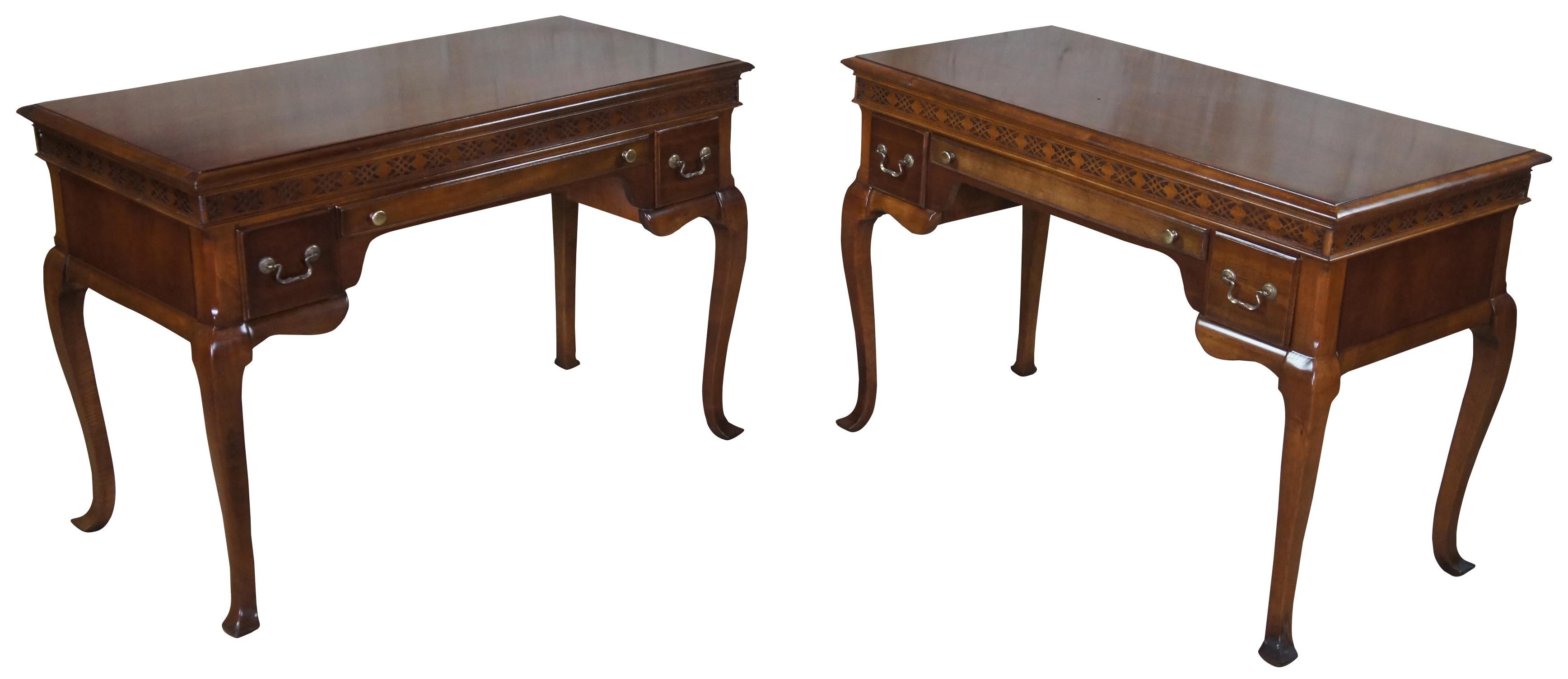 A beautiful pair of early 20th century cherry Queen Anne library desks. Features a rectangular form with ogee edge over fretworked apron. A pencil drawer at the center is flanked by 2 additional drawers. The desk is supported by cabriole legs