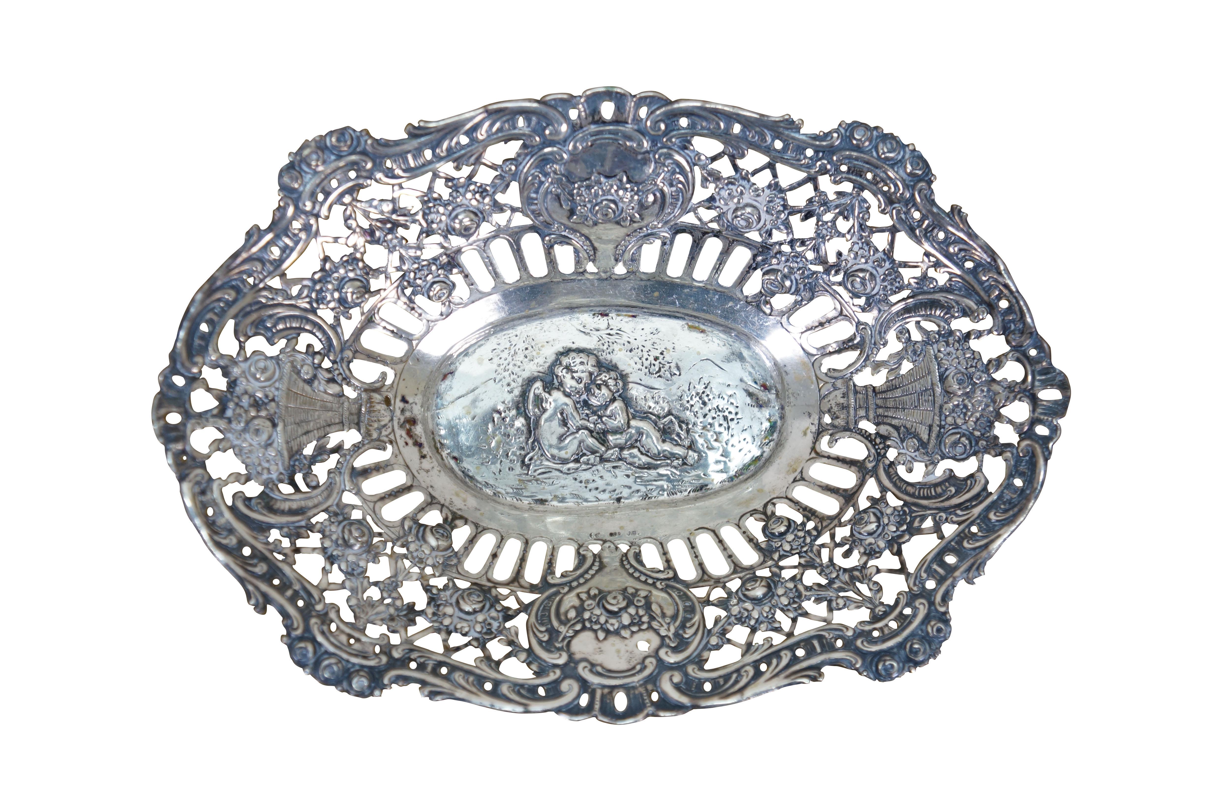 Pair of antique 800 German silver repousse reticulated dishes / baskets. Oval form with scalloped edge, pierced sides with foliate designs, surrounding central motifs of cherubs / putti angels.

Dimensions:
Larger - 8.25