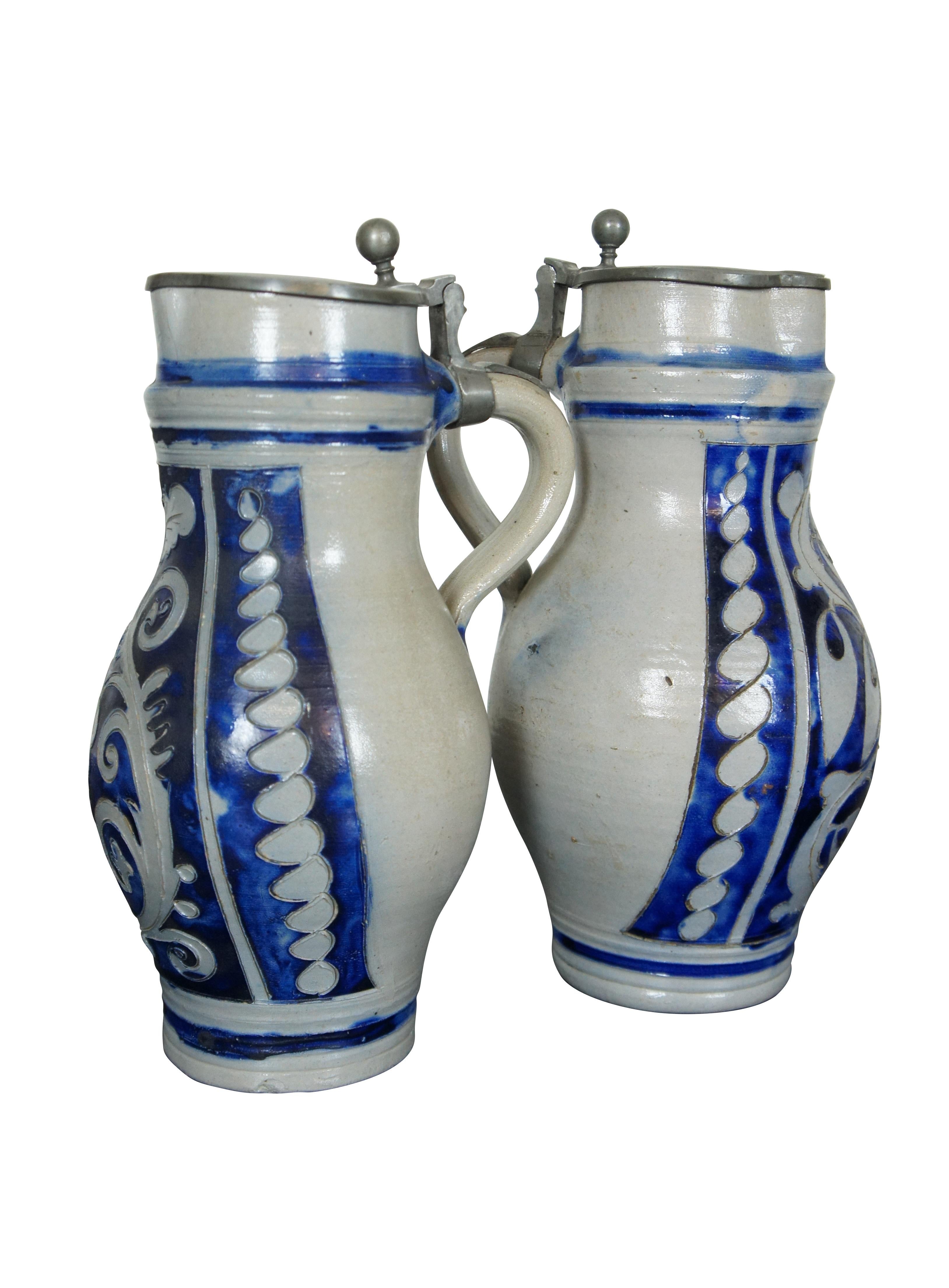 Two antique 19th century German Westerwald cobalt blue salt glaze creamer pitchers / beer steins / jugs featuring pewter lids and floral / leaf motif.  1.5L.  Birnkrug.

DIMENSIONS

7.5” x 6.5” x 12.25” (Width x Depth x Height)
