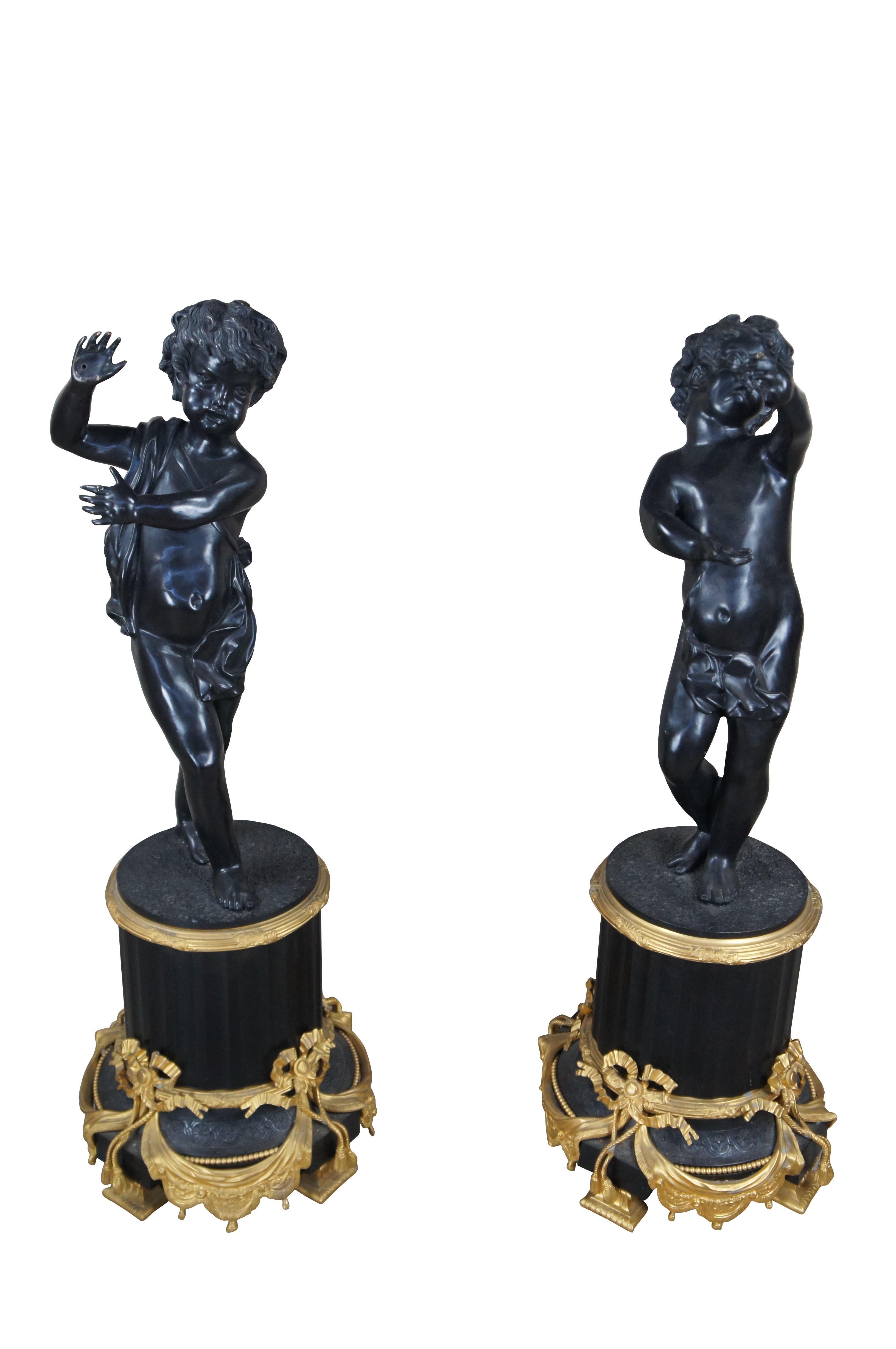Pair of Monumental Italian Neoclassical Cherub Putti Sculptures.  Made from bronze with ebonized and gilt detail. Each raised over a classical fluted and footed column plinth with ornate ribboned swags. The cherubs are standing with their hands