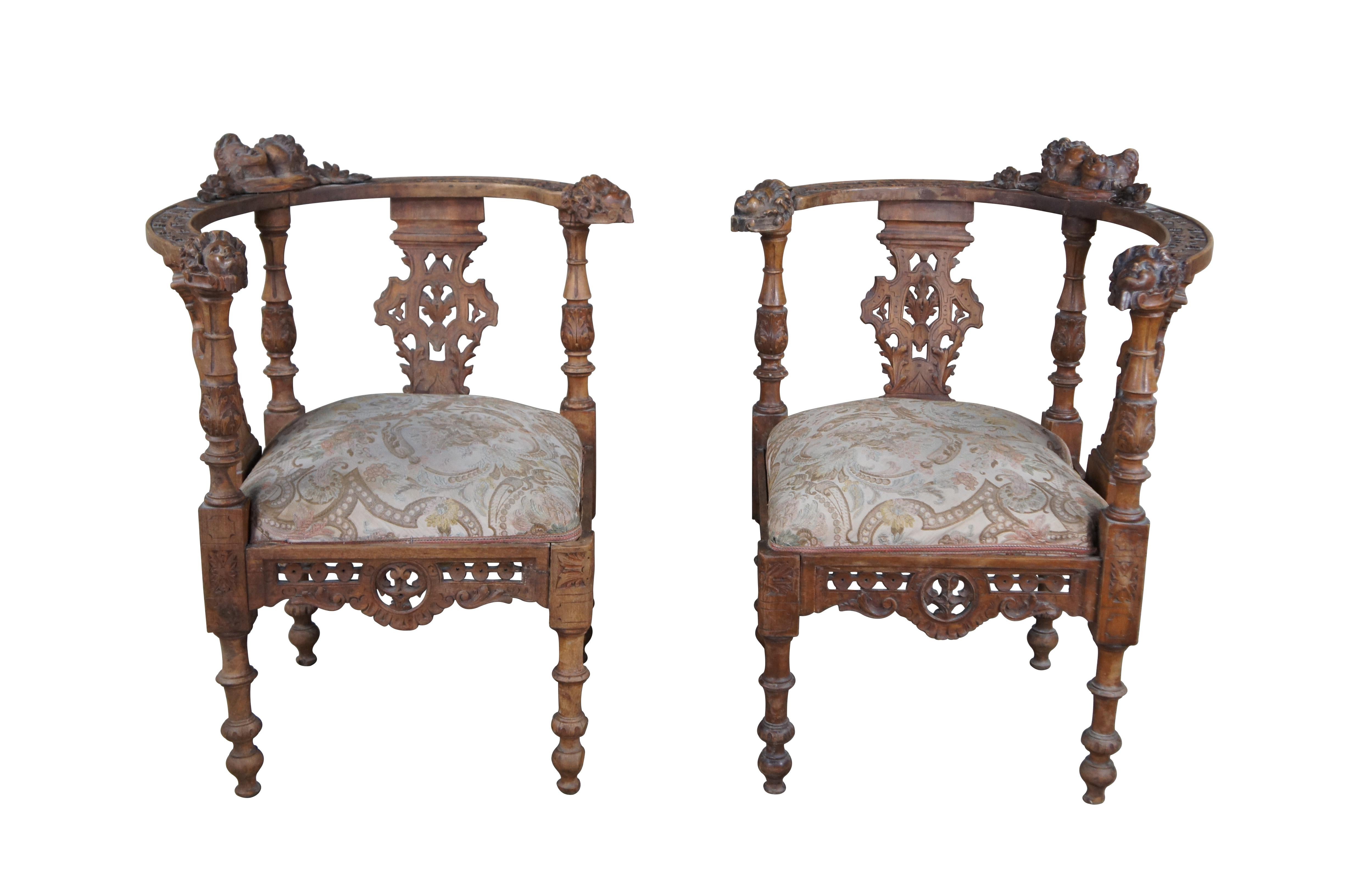 Paire de chaises d'angle italiennes anciennes de style néo-renaissance, vers les années 1870. Réalisée en noyer, elle présente un style néoclassique avec des sculptures en haut-relief d'angelots/puttis sur des dossiers à feuillage ajouré et des
