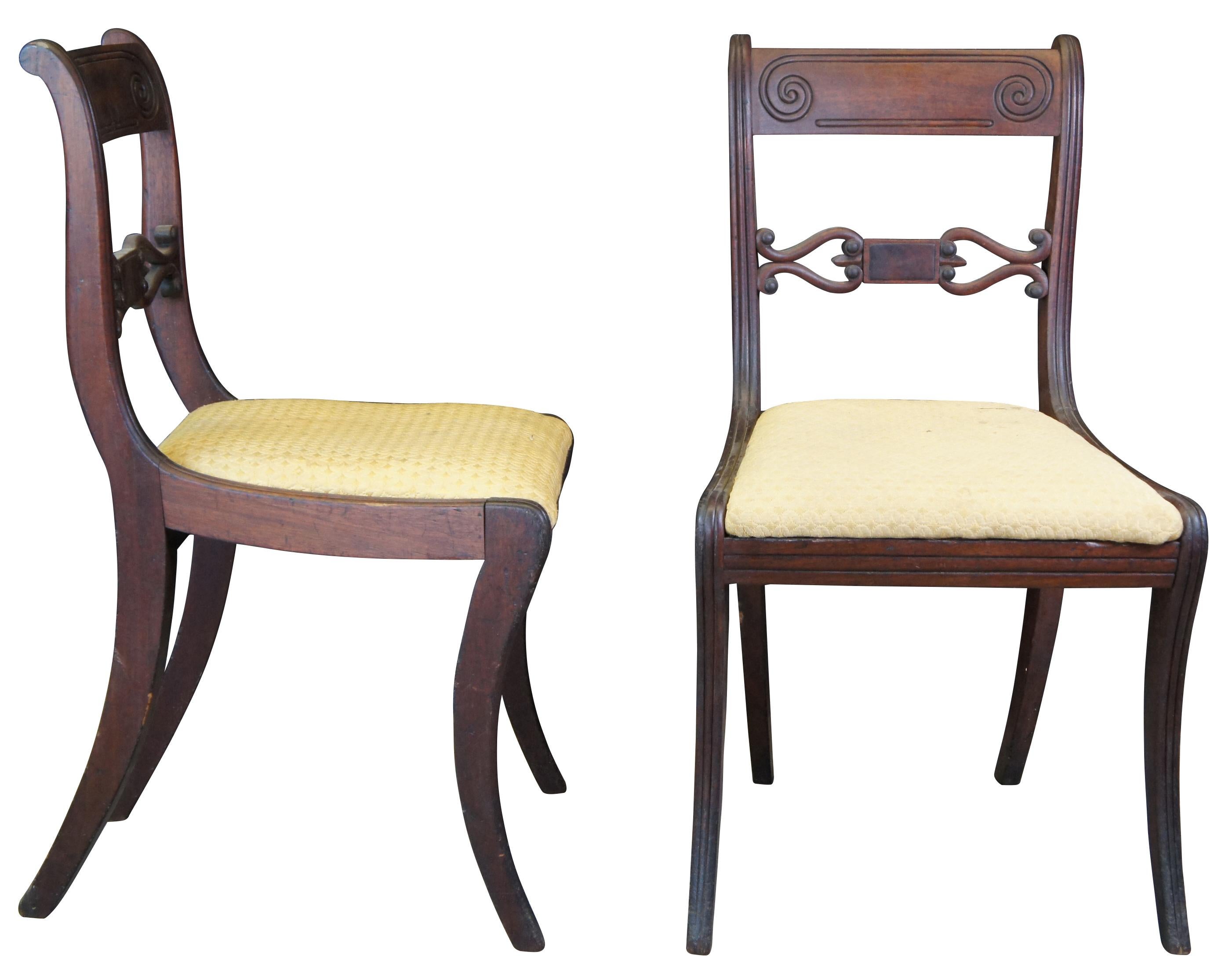Two antique Duncan Phyfe Klismos style side accent dining chairs. Made of mahogany featuring open back with carved and fluted accents. Measure: 33