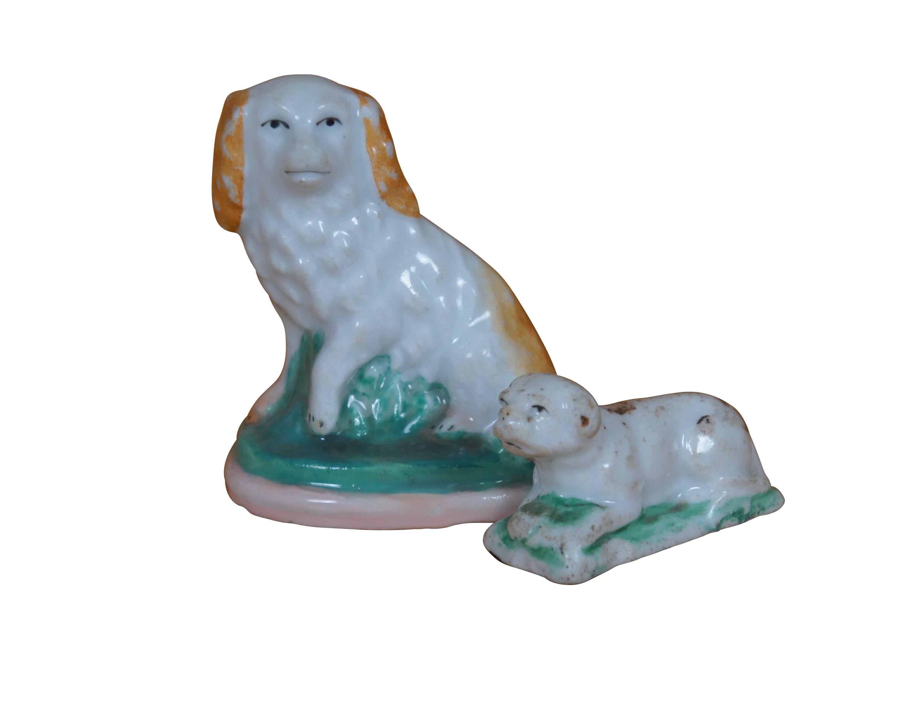 Coppia di antiche statuine in porcellana Staffordshire a forma di cane: uno spaniel Charles Charles bianco e rosso seduto su una base erbosa e un bulldog reclinato con macchie marroni.

Dimensioni:
Più grande - 2,5