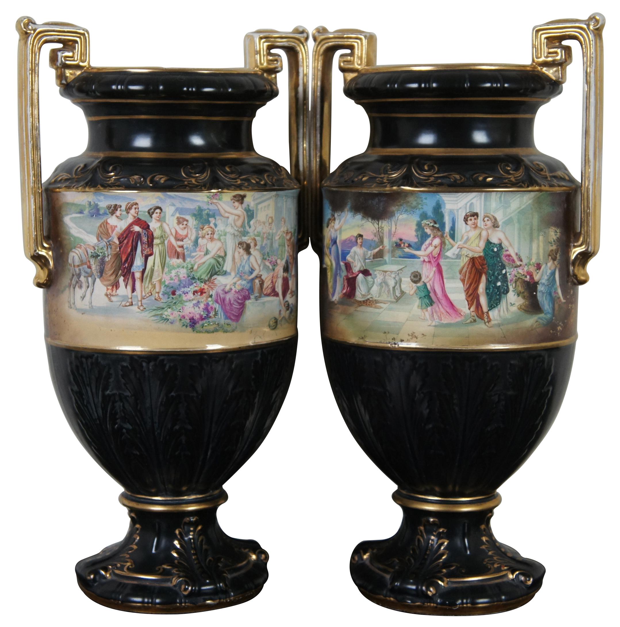 Two black porcelain mantel vases in the shape of Grecian urns with Greek key handles, acanthus leaves, gold accents and idyllic scenes of figures, signed Lesoir. Made in England.
  