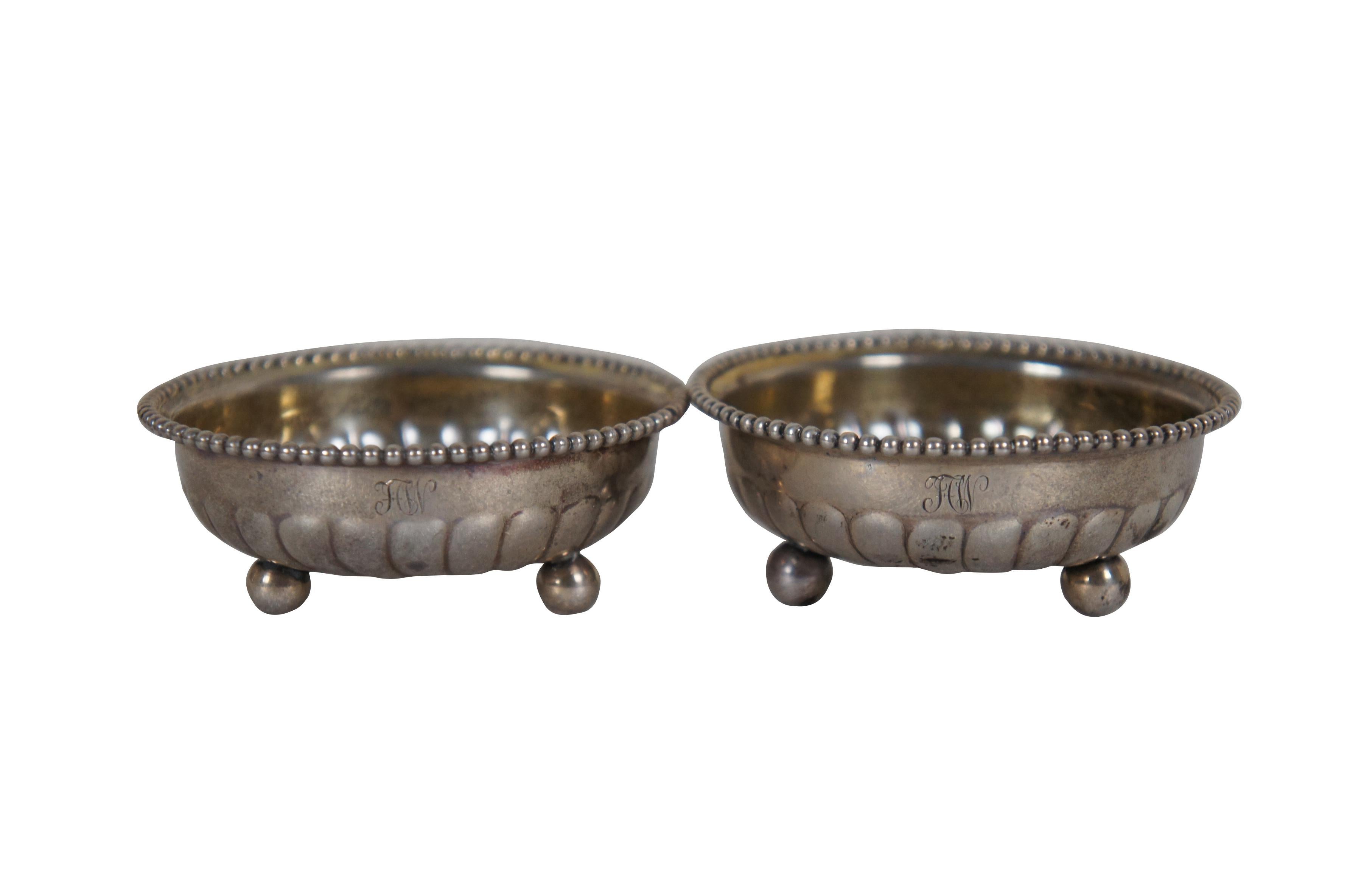 Late 19th century pair of sterling silver salt cellar / bone dishes by Tiffany & Co. Round form with fluted base, beaded edge, ball feet. Monogram FCW. Date mark T indicates production under Tiffany president Charles L. Tiffany, circa 1891-1902.
