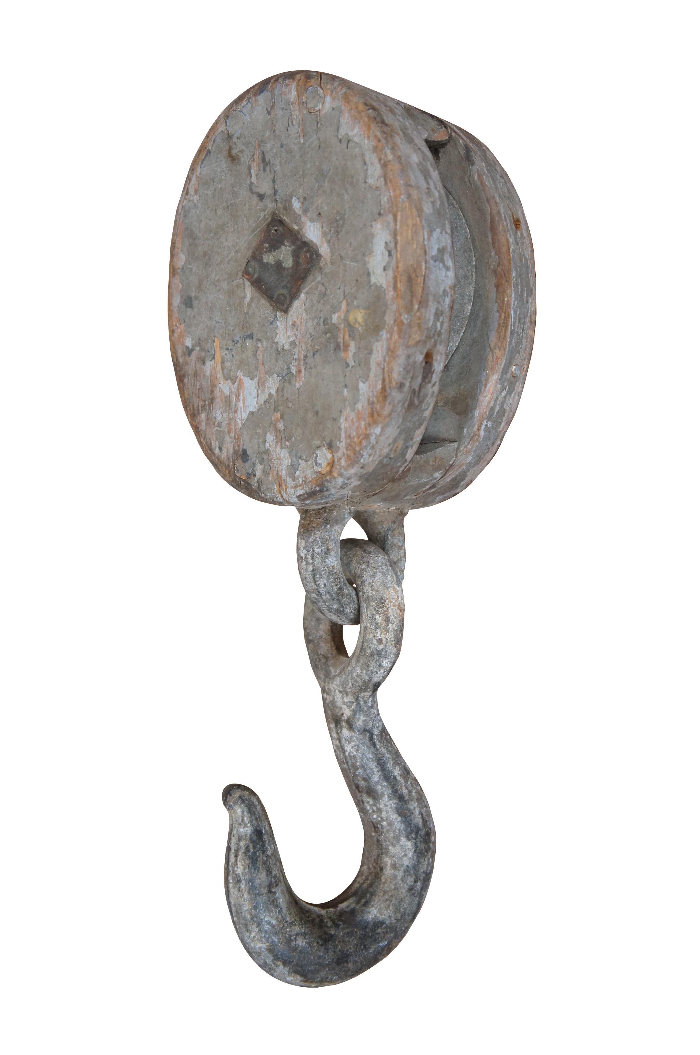 Pair of antique wood block and iron industrial pulley hooks. Larger has one pulley wheel, smaller contains two pulley wheels.

Dimensions:
Large - 5