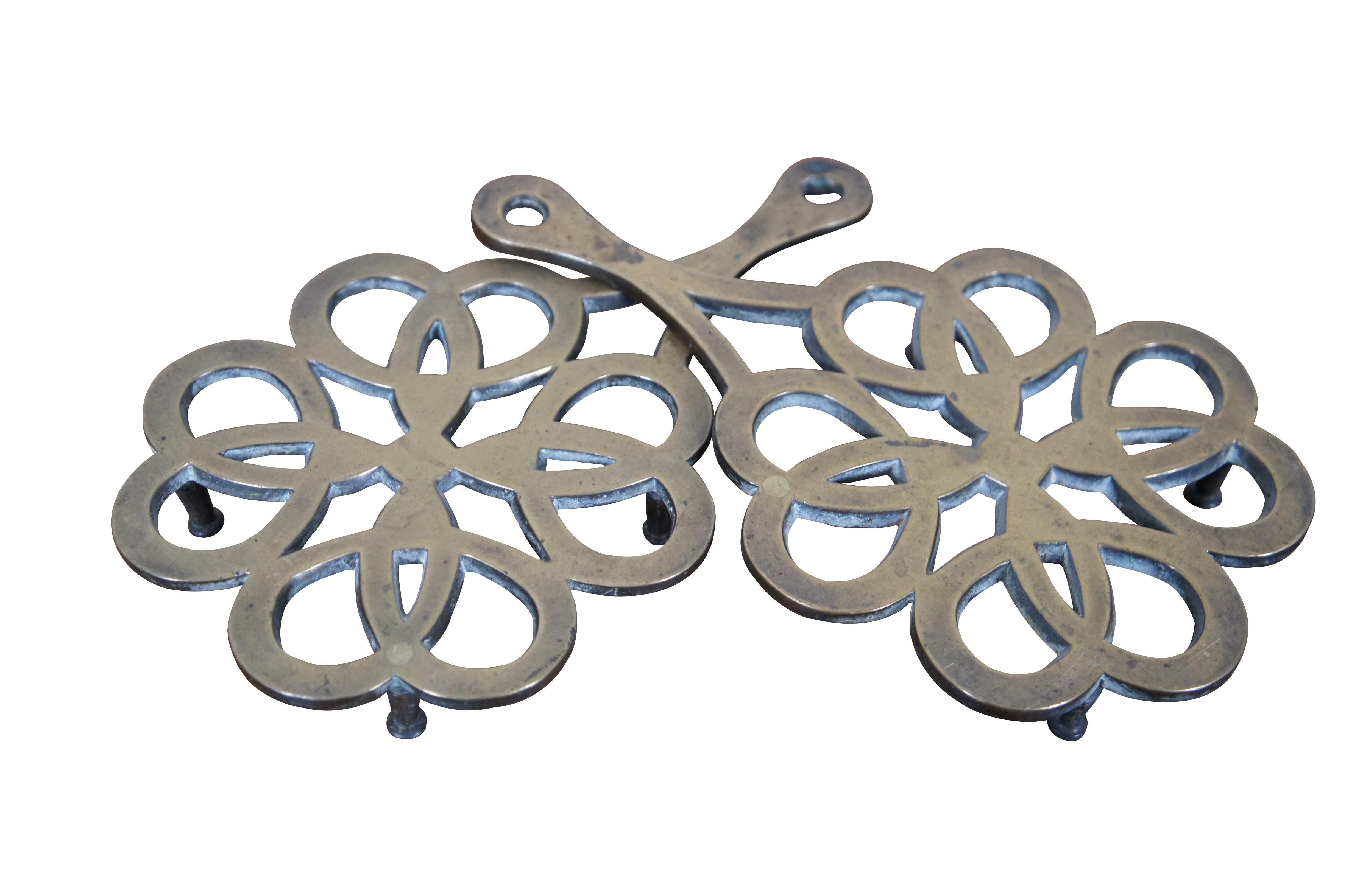 Two antique brass fireplace trivets / kettle rests featuring a reticulated pierced floral design with footed base.

Dimensions:
10