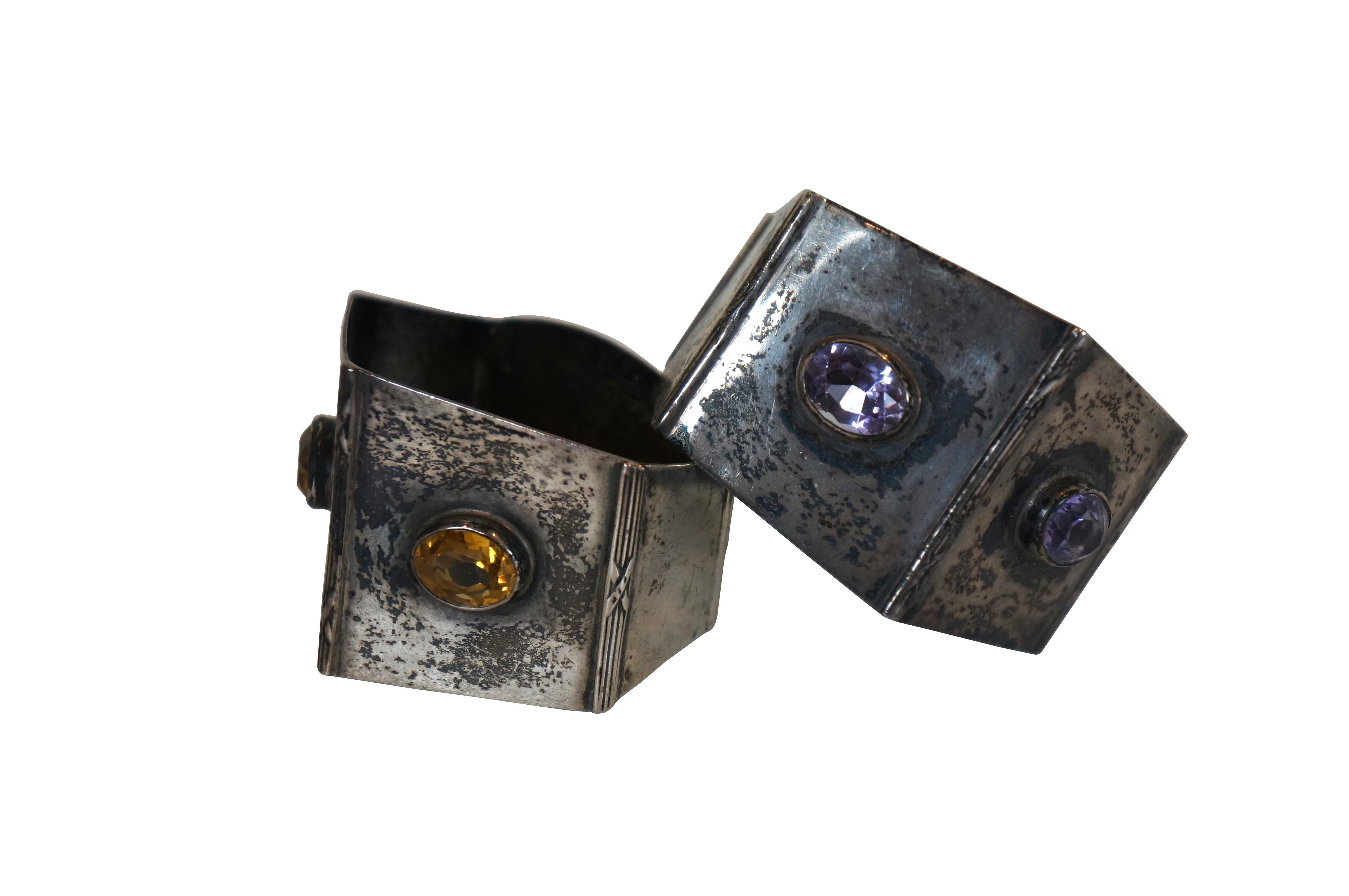 Pair of early 20th century Arts and Crafts style sterling silver and gemstone napkin rings, produced in 1910 by Birmingham silversmith Robert Chandler (maker's mark used circa 1901-1924). Pentagonal shape accented with a pair of faceted stones -