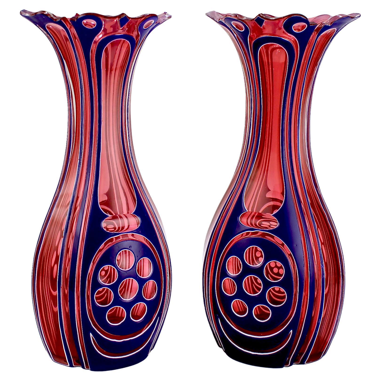 Une belle et très rare paire de vases anciens en verre taillé de Bohème à trois couleurs.

Chacun d'entre eux est recouvert d'épaisses couches de verre bleu et blanc sur fond de canneberge et taillé à la roue avec des motifs géométriques. 

Les