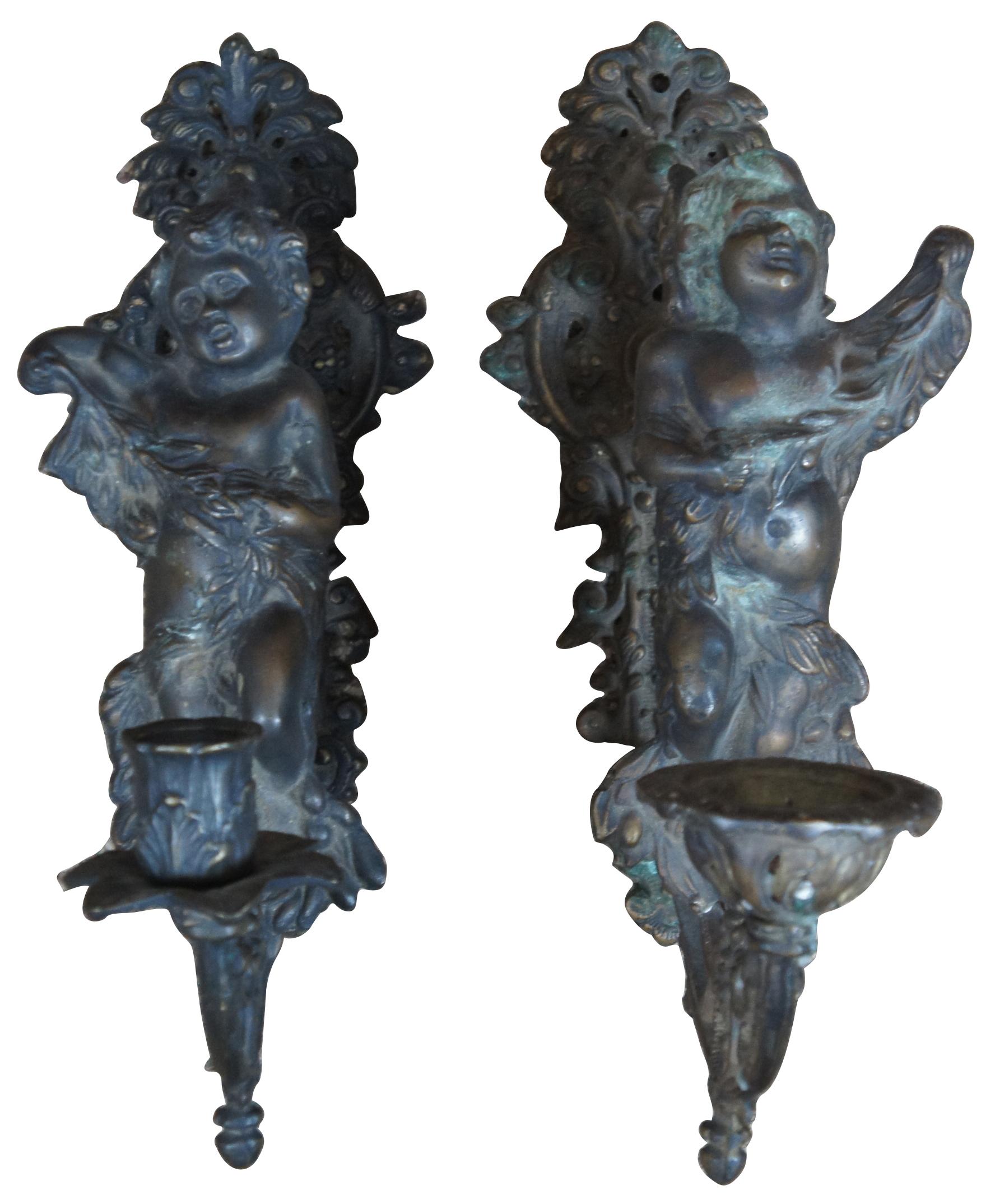 Two heavy bronze 19th century Victorian figural wall sconces. Features ornate scrolled back leading to cherubs which continue to the candle holder. A face ordains the back plate which appears to be Dionysus or Bacchus.