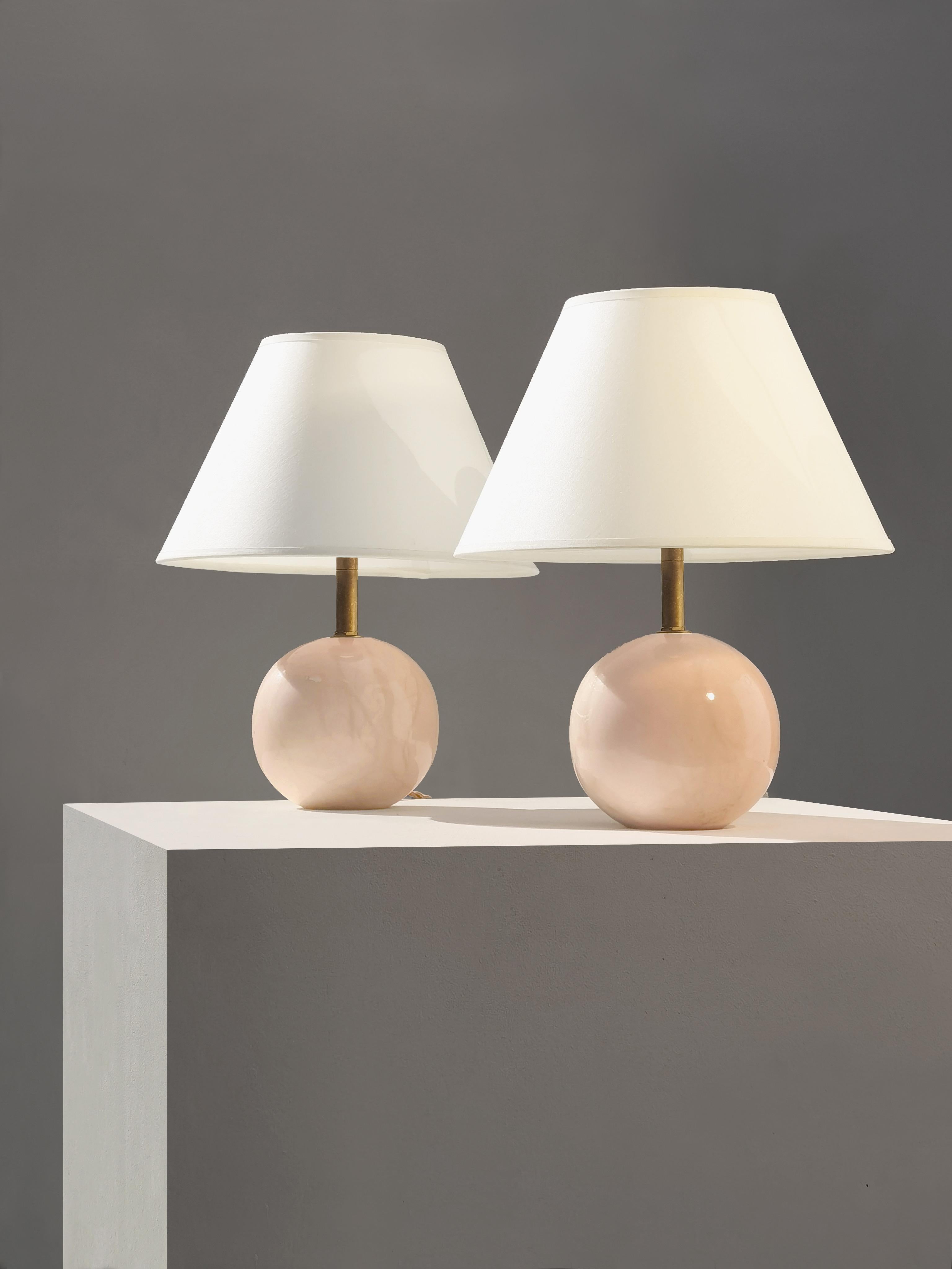 Pequeña y elegante pareja de lámparas esféricas de sobremesa de mármol rosa, a atribuir, Francia 1960.
2 pequeñas pero macizas esferas de mármol rosa forman los cuerpos de las 2 lámparas, mostrando sutiles dibujos marmóreos, cubiertos por un barniz