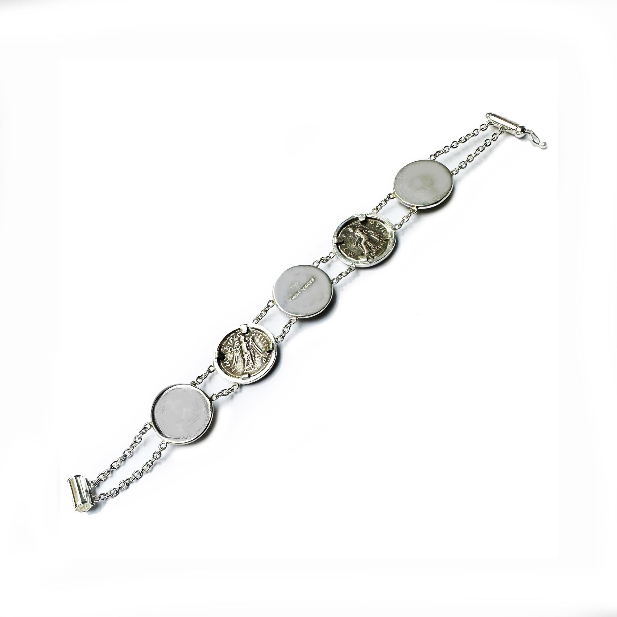This exquisite sterling silver bracelet features the remarkable addition of two authentic Roman coins from the 2nd century AD, depicting the revered Emperors Hadrian and Trajan. Alongside these ancient coins, the bracelet showcases the timeless