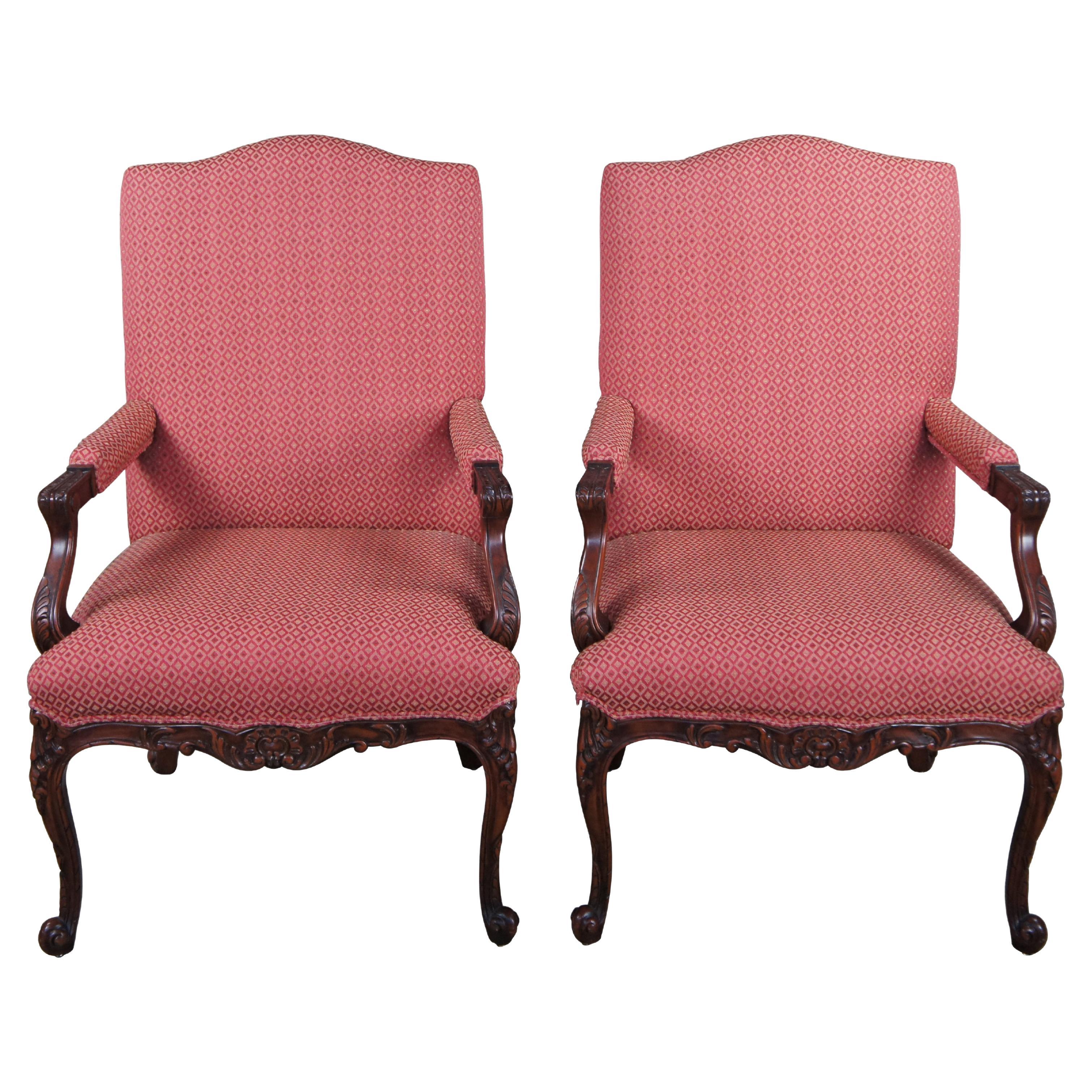 Pair of Baker Furniture library or lounge arm chairs, circa 1980s.  Made of mahogany featuring French Louis XVI styling with domed / serpentine top, padded fauteuil arms, carved acanthus foliate motif and cabriole legs.  Very