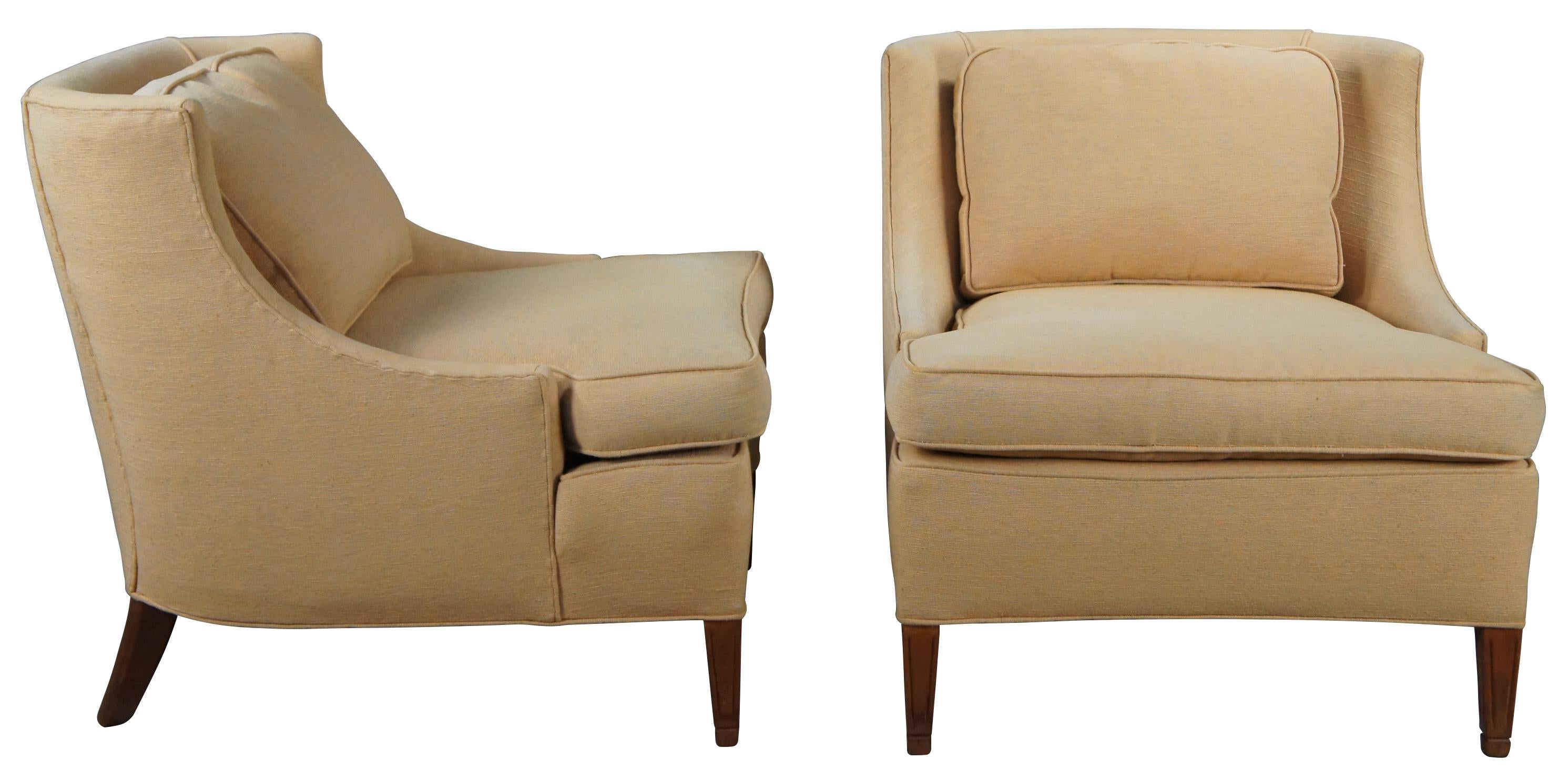 Pair of mid century slipper wingback chairs by Baker Furniture. A sleek design with light yellow cotton upholstery and walnut finished square tapered legs. 
 