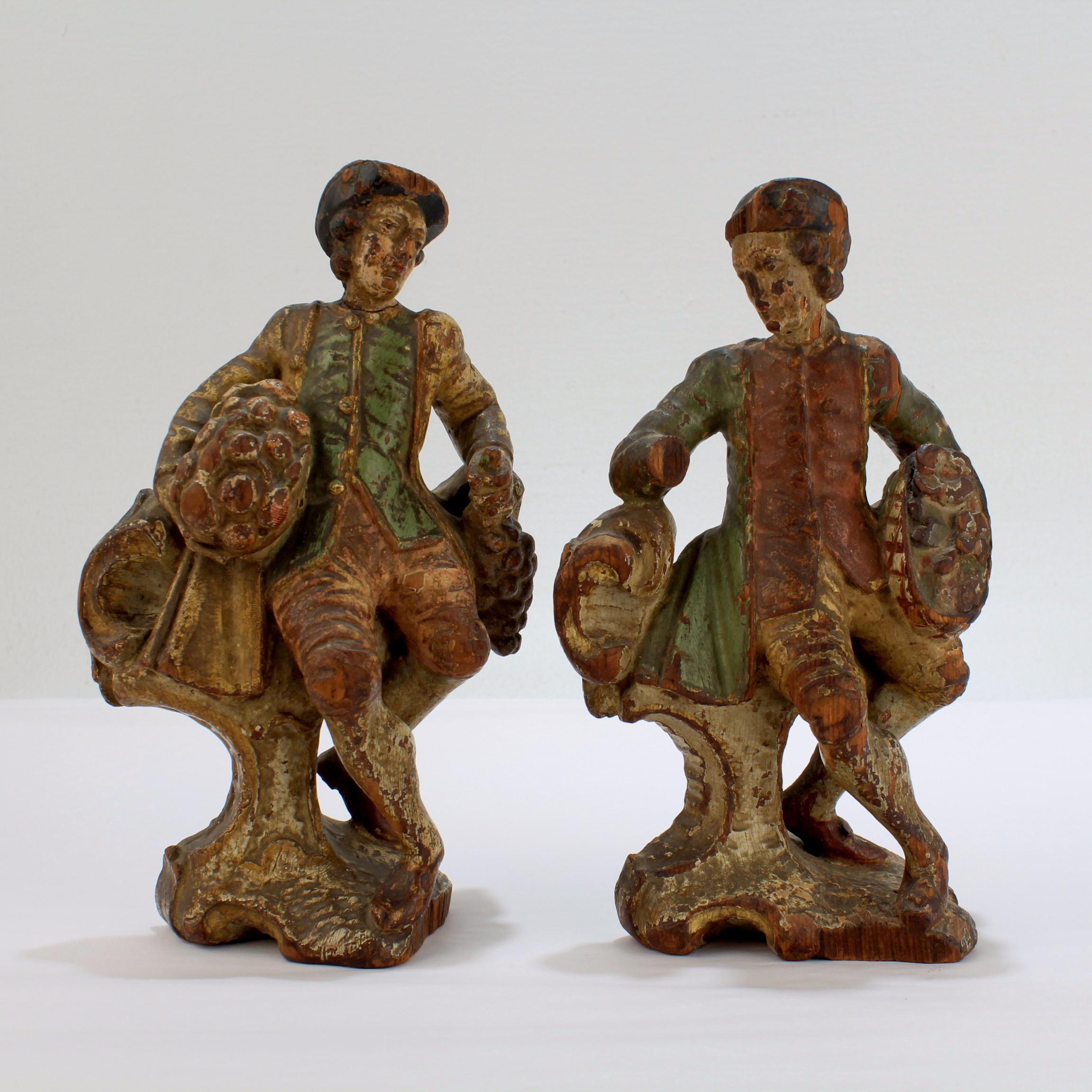A pair of 18th century carved wooden figurines

Likely Central European originating somewhere in Germany, Austria, Switzerland, or Northern Italy. 

Both figurines depict a gallant gentleman in period dress holding a basket replete with fruit or