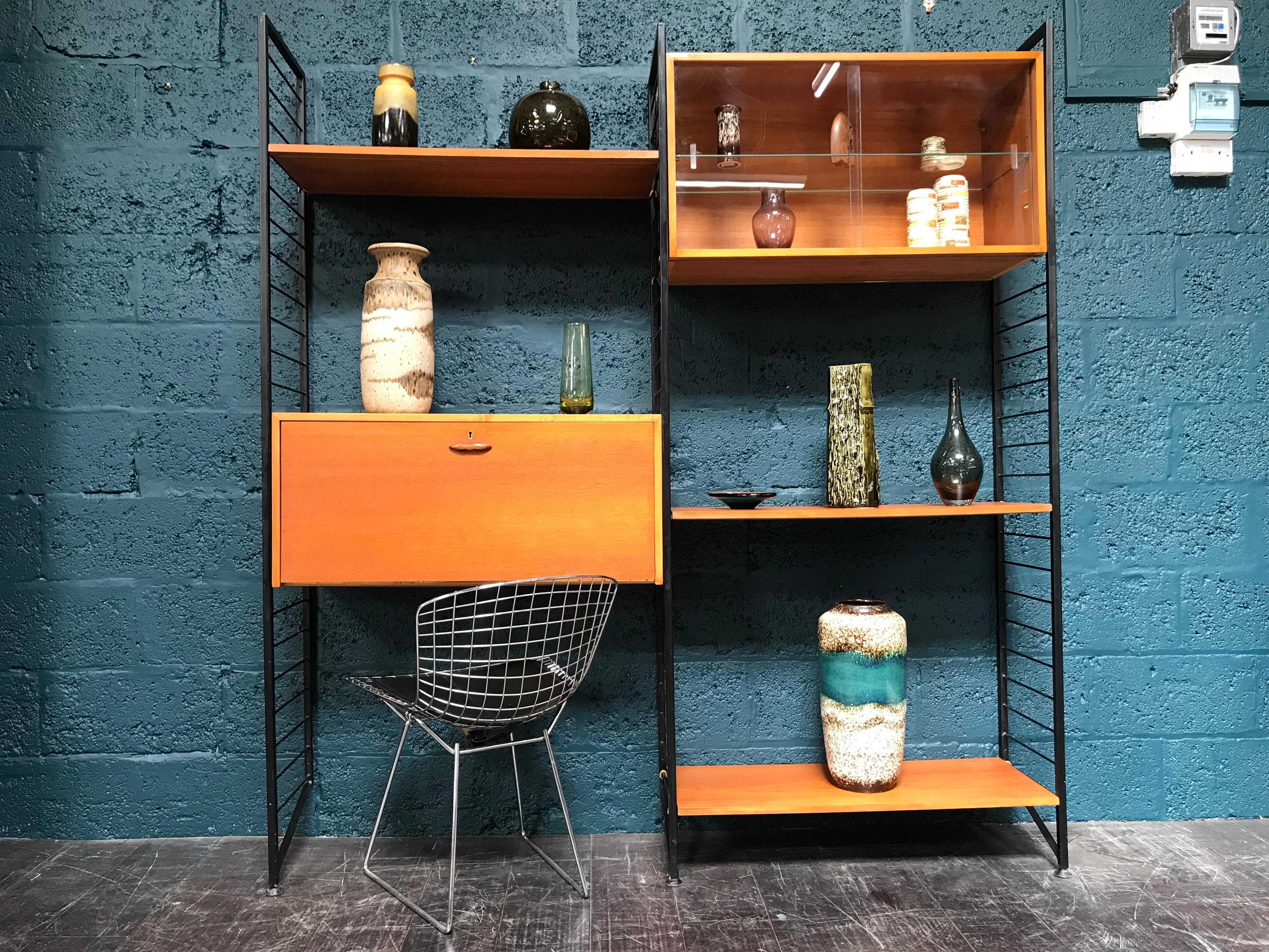 Stylish and functional, this is the classic Staples Ladderax mid century shelving system. The black metal uprights and easy removable supports, allow the teak cabinetry to be positioned wherever required. This is a very versatile piece of retro