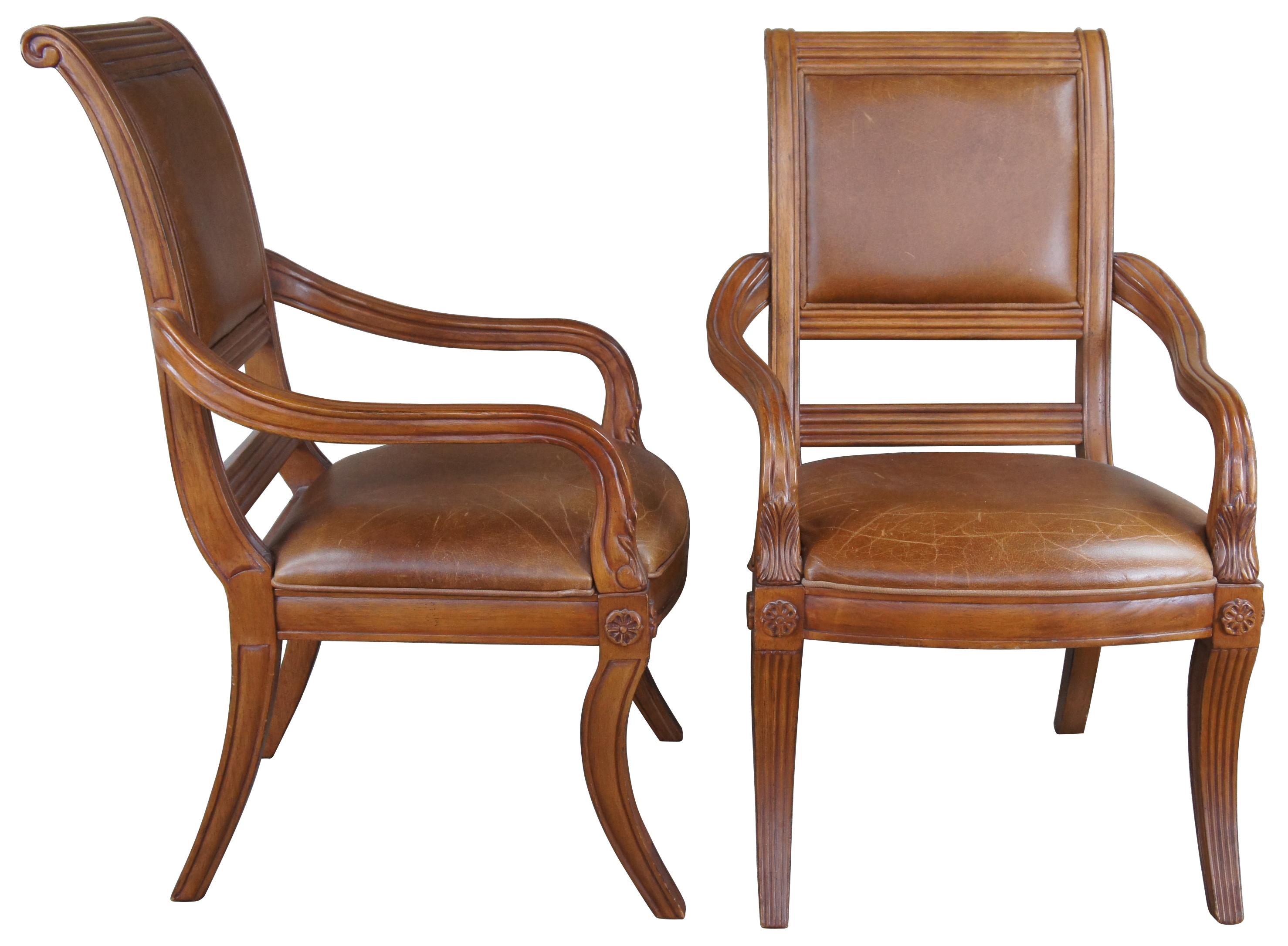 A lovely pair of chairs by Bernhardt Furniture Company. Drawing inspiration from Empire, Regency and Neoclassical styling. Hardwood frames with brown leather upholstery. Features a scrolled back with carved wreath design along the back, medallions,
