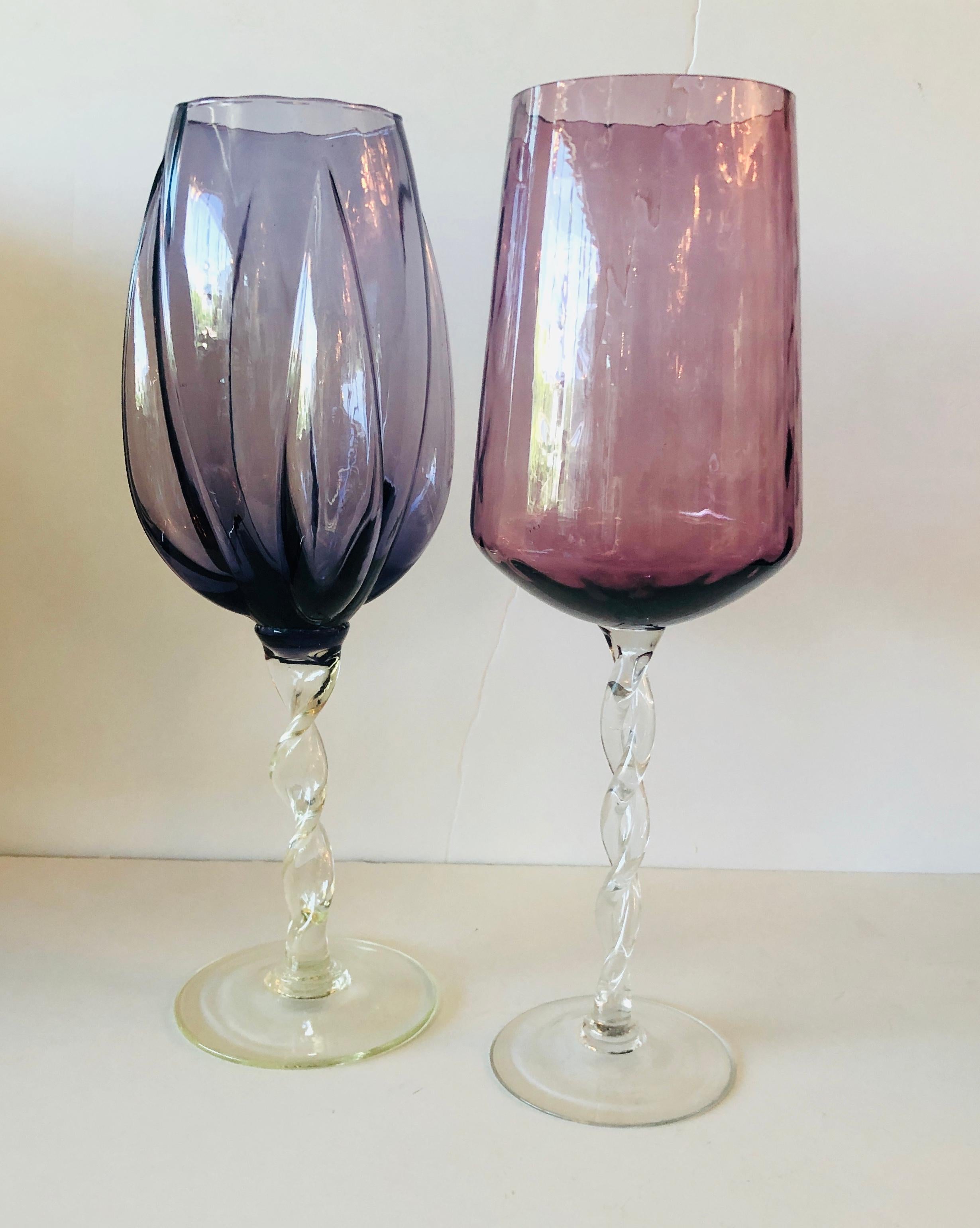 Offered are two hand blown Mid-Century Modern over-sized glass brandy snifters or vases in cranberry red / pink and eggplant purple with braided clear stems. Would look great as decor, with flowers or on a bar or bar cart. Can be purchased as a set
