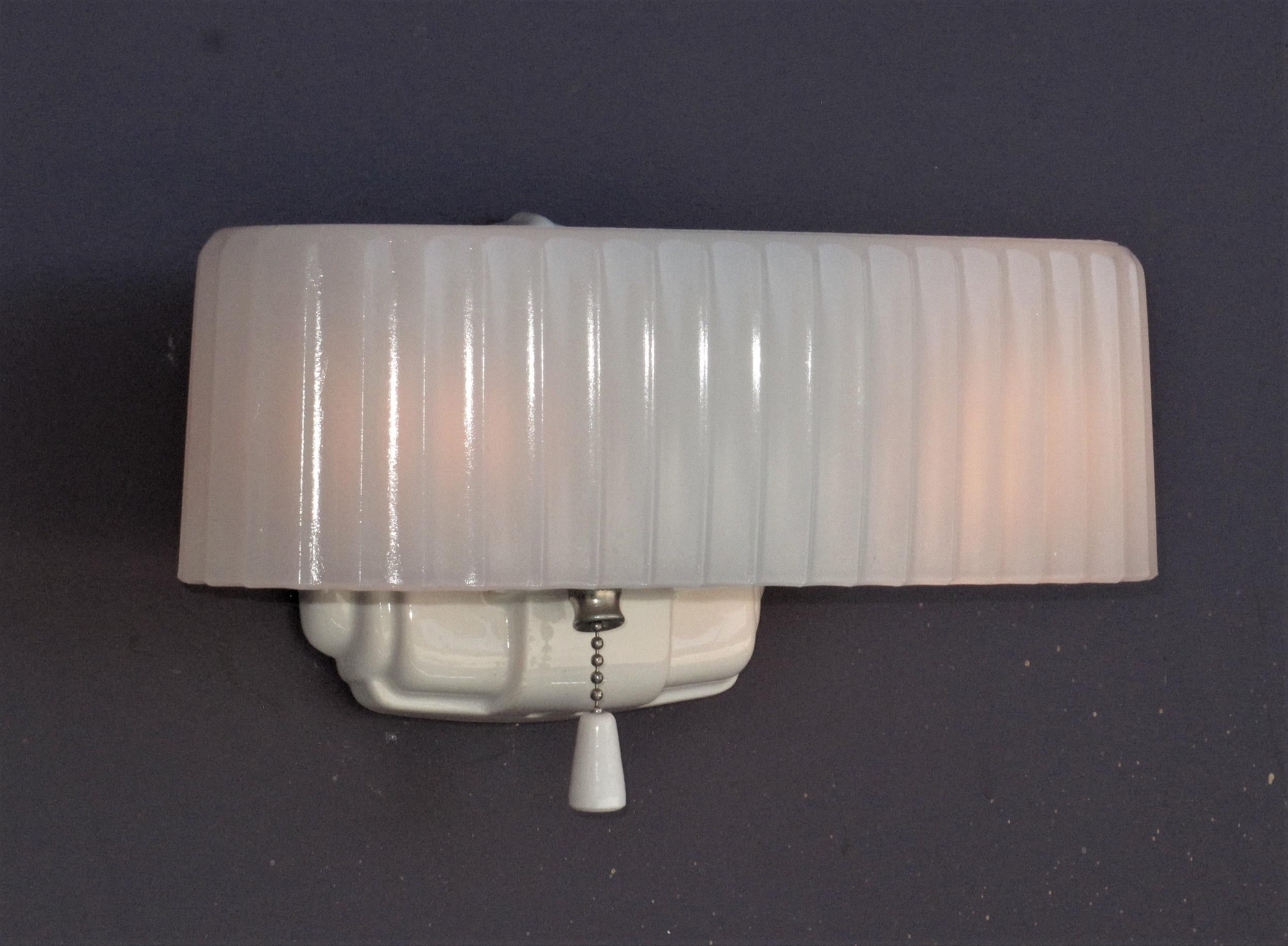 90 year old (approx) white porcelain sconce back with a ribbed clam broth or camphor glass shade. Both porcelain back and glass shade in excellent condition with no chips or cracks.
Will integrate perfectly into a vintage or modern bathroom or