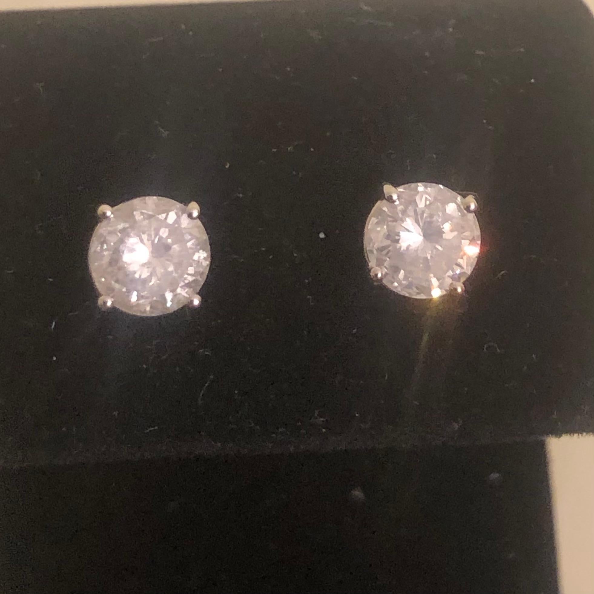 Stunning 2 Ct Brilliant Round Solitaire Diamond Stud Earrings in 14K White Gold. These natural diamond studs are certified with an appraisal report value of $8,850.00.

A large center 1 carat plus solitaire diamond (size of an engagement ring) is