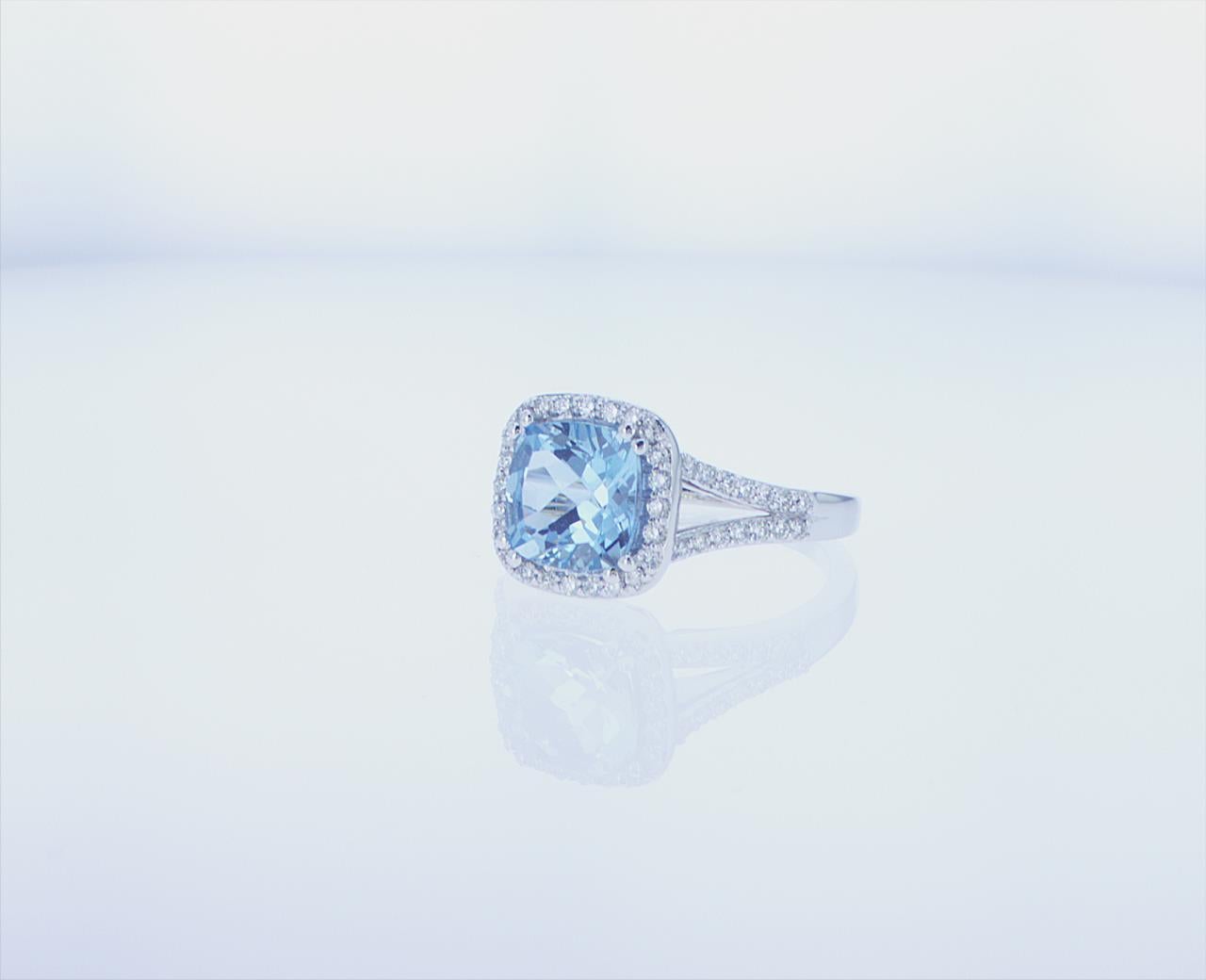 2.08ct Cushion Shaped Aqua Cocktail Ring with Split Diamond Shank featuring 0.40ct total weight of G/H Color, VS Clarity Round Brilliant Diamonds in a 14k White Gold mounting.
