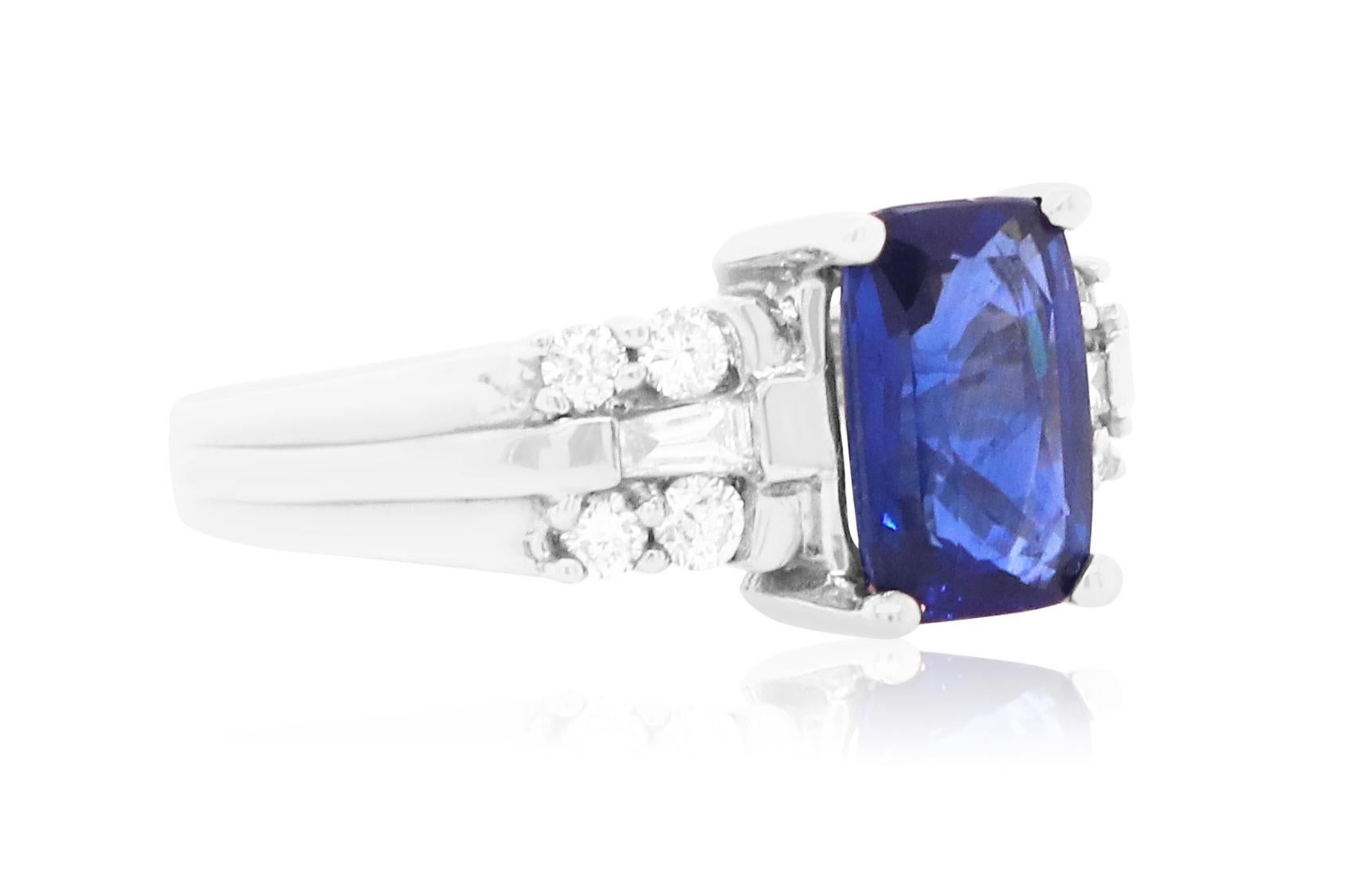 Material: 18k White Gold 
Center Stone Details:  1 Cushion Cut Blue Sapphire at 2 Carats 
Mounting Diamond Details: 2 Baguette Diamonds at 0.10 Carats - Clarity: VS-SI / Color: G-H
Diamond Details: 8 Brilliant Round White Diamonds at Approximately