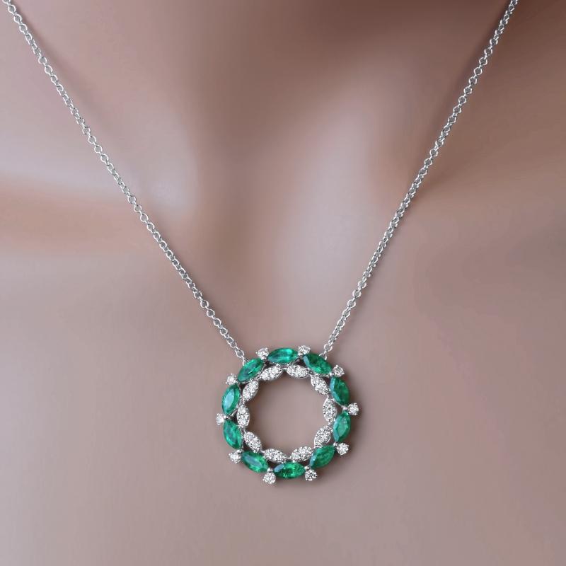 This pendant features approximately 2 carats of marquise cut fine emeralds, in a circle shape. A second internal circle is made of round diamonds set in clusters to give the impression of marquise diamonds. Additional round diamonds bring the total