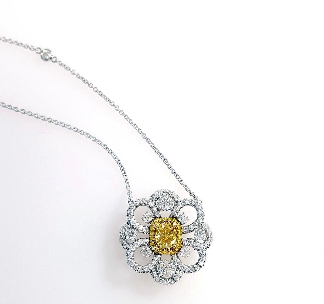 Introducing a captivating flower-inspired open-style design pendant necklace adorned with a center of 0.73-carat cushion-cut Fancy Vivid Yellow diamond, certified by GIA with an SI1 clarity rating. This remarkable centerpiece is encircled by a halo