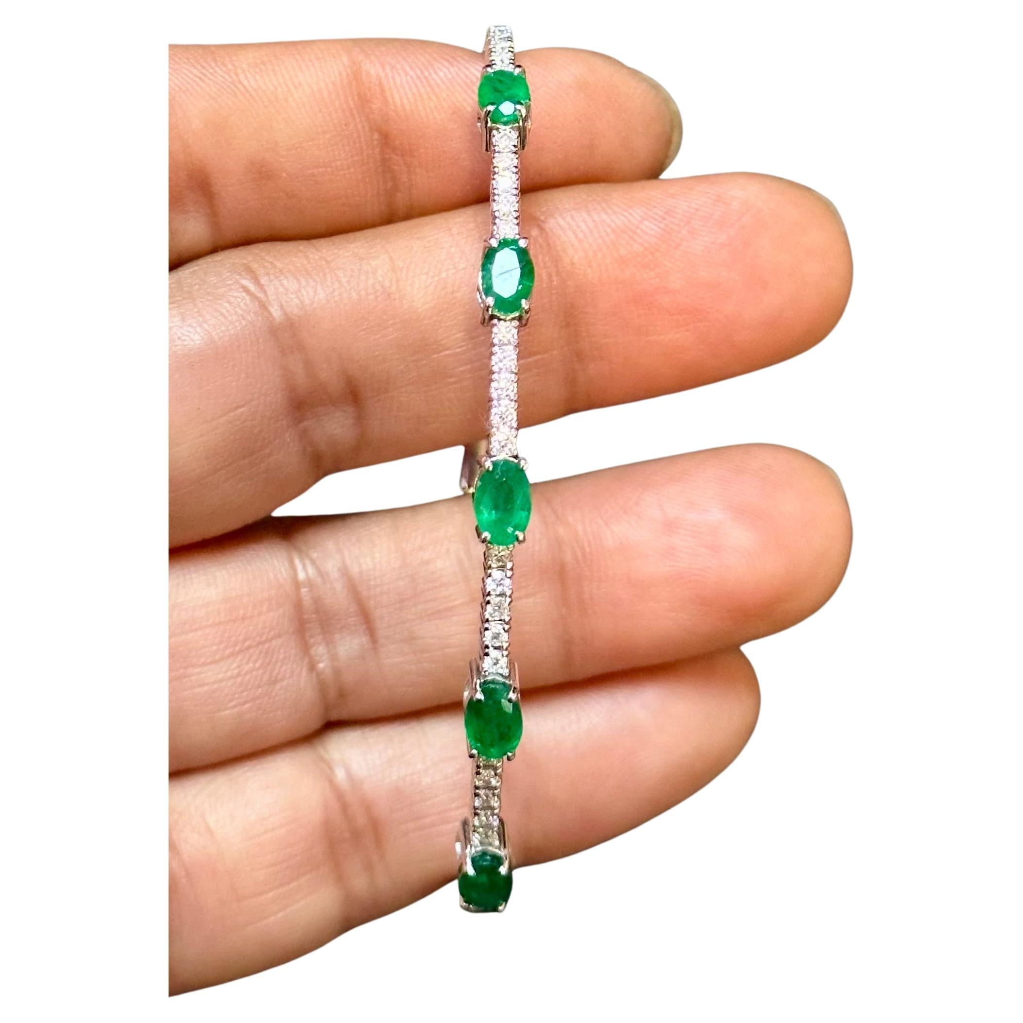 Introducing our stunning 14 Karat White Gold Bangle Bracelet adorned with approximately 2 carats of Natural Brazilian Emeralds and shimmering diamonds. This exquisite piece showcases five oval-cut emeralds, each separated by a row of brilliant-cut