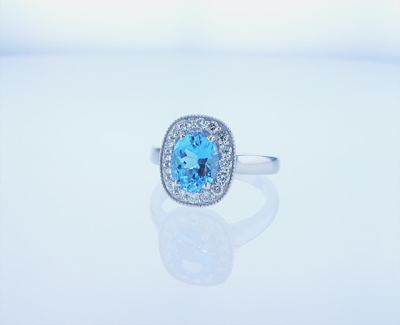 Oval 2.29ct Blue Topaz with 0.51ct total weight of G/H Color, VS Clarity Round Brilliant Diamonds framing the center. 18k White Gold Mounting.