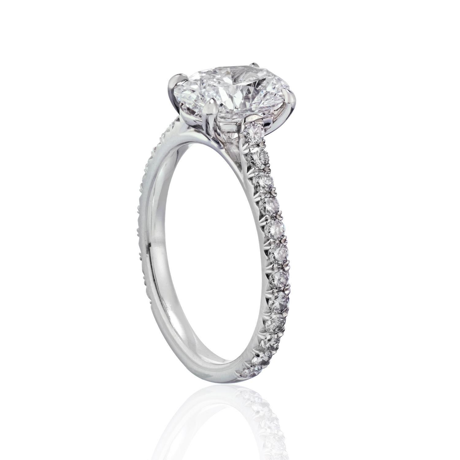 This oval cut diamond solitaire is set in a handmade four prong platinum mounting with diamond pavé band. Our engagement rings are hand-crafted in New York, custom tailored to any desired specification and utilizing GIA certified diamonds. This