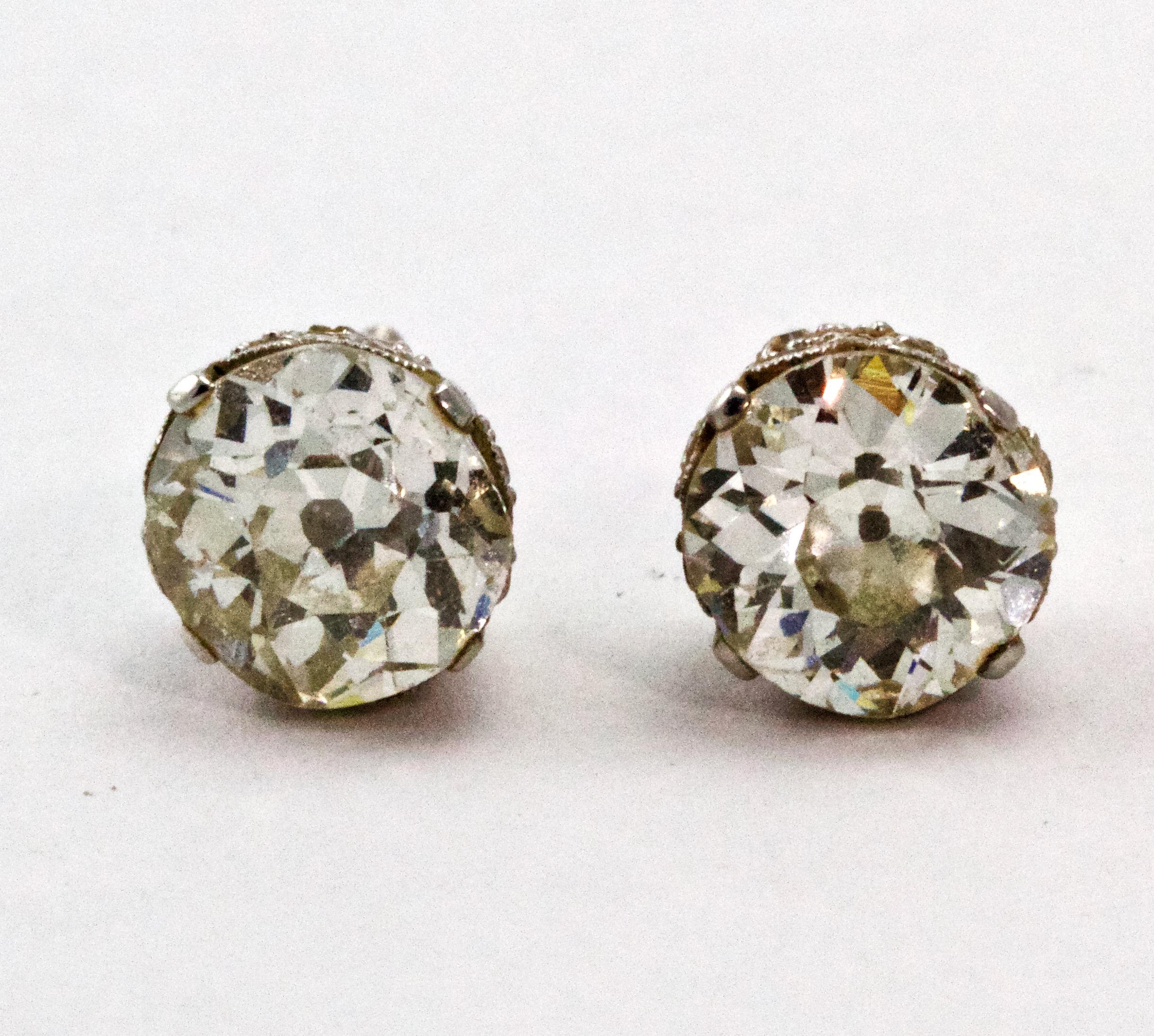 A spectacular pair of Art Deco diamond stud earrings. Showcasing two Old European Cut diamonds in diamond embellished coronet settings, complete with screw back fittings and modelled in platinum throughout. 
Diamonds : 1 carat 15 & 1 carat 17 (I -