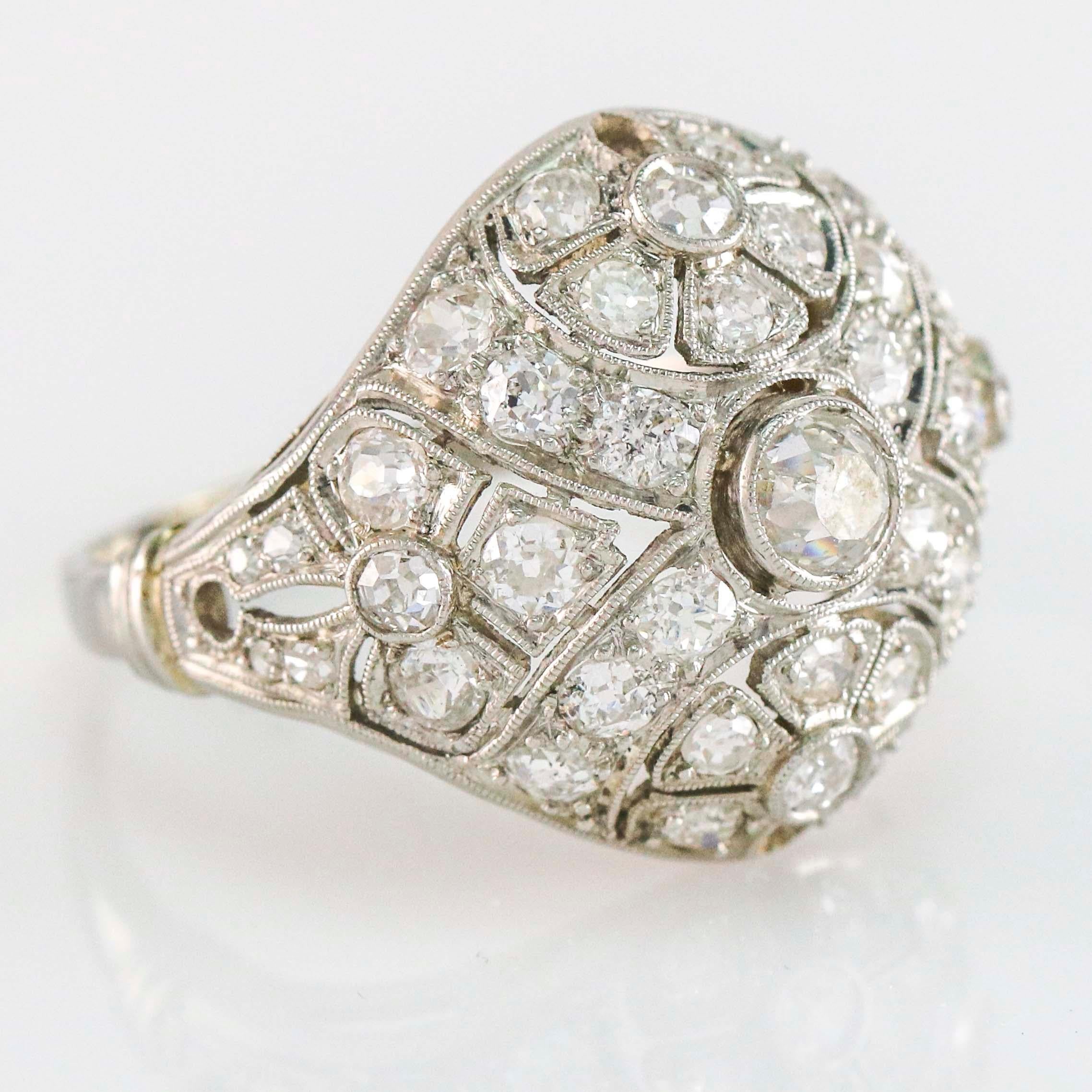 Edwardian diamond dome ring in platinum. The ring features a floral design with filigree and openwork.