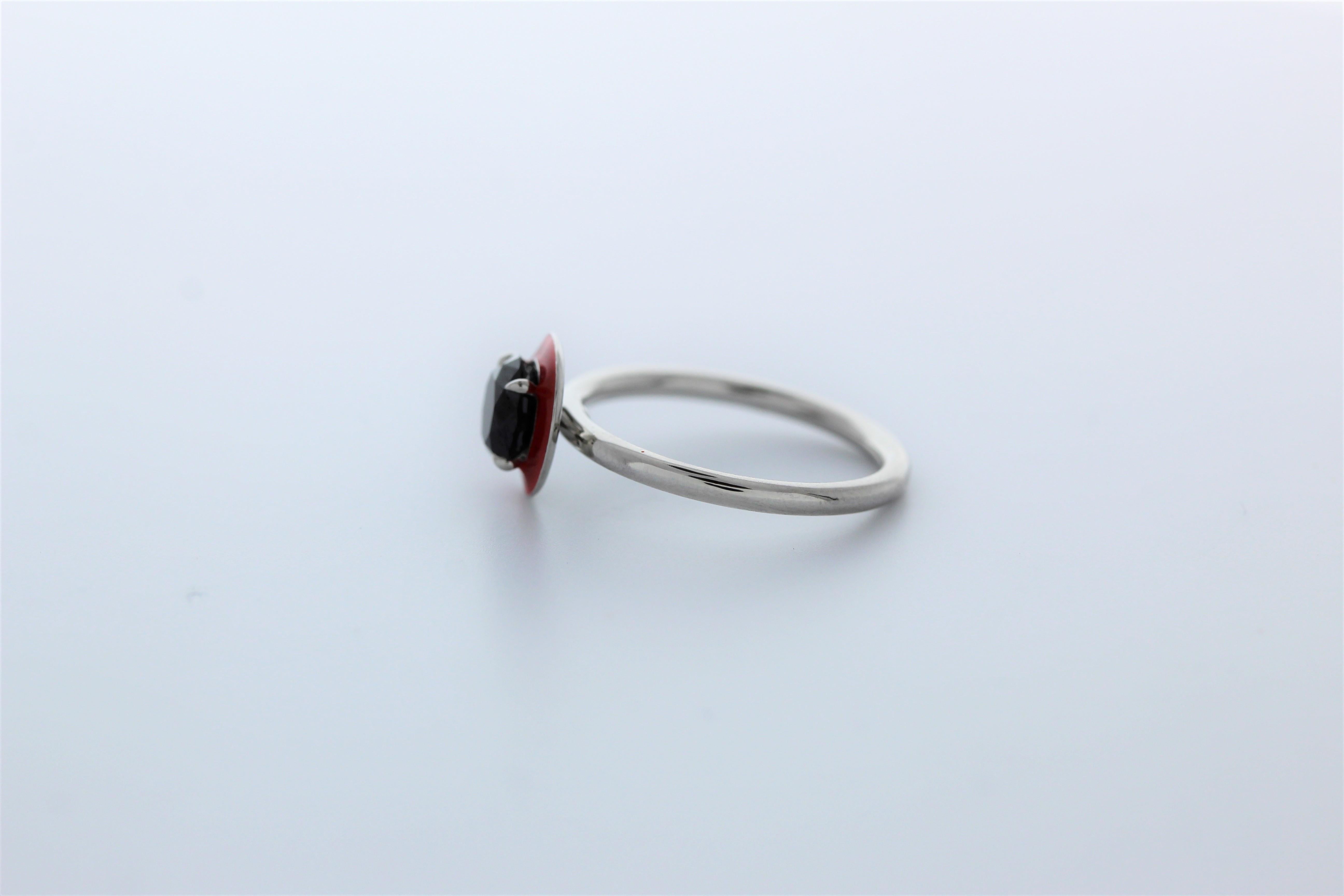 This modern natural black diamond and red enamel ring is perfectly designed.  The center 2 carat round brilliant diamond is prong set in a platinum measuring 7.25 x 7.24 x 5.32 mm.  The center diamond is accented with rich red enamel creating a halo