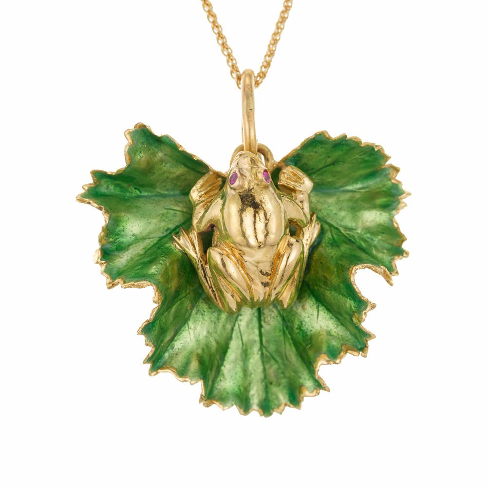 1970's Pendant necklace. Green enamel leaf and 3D frog pendant with 2 round ruby eyes. The frog is 18k yellow gold as is the underneath of the enameled leaf. This one of a kind unique piece dangles from an 18 inch,  18k yellow gold chain. 

2 round