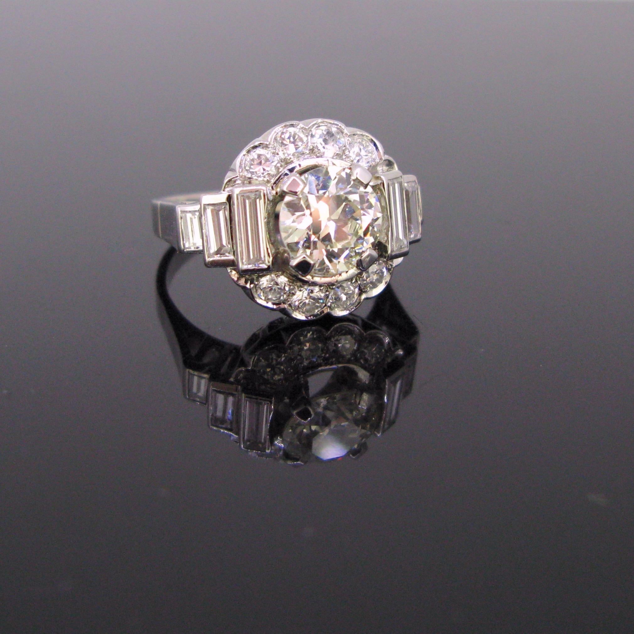  This beautiful Art Deco ring is made in platinum. It is set with a 2ct approximately transitional cut diamond surrounded with old European cut diamonds and shouldered on the sides with baguette diamonds. The total diamond carat weight is about
