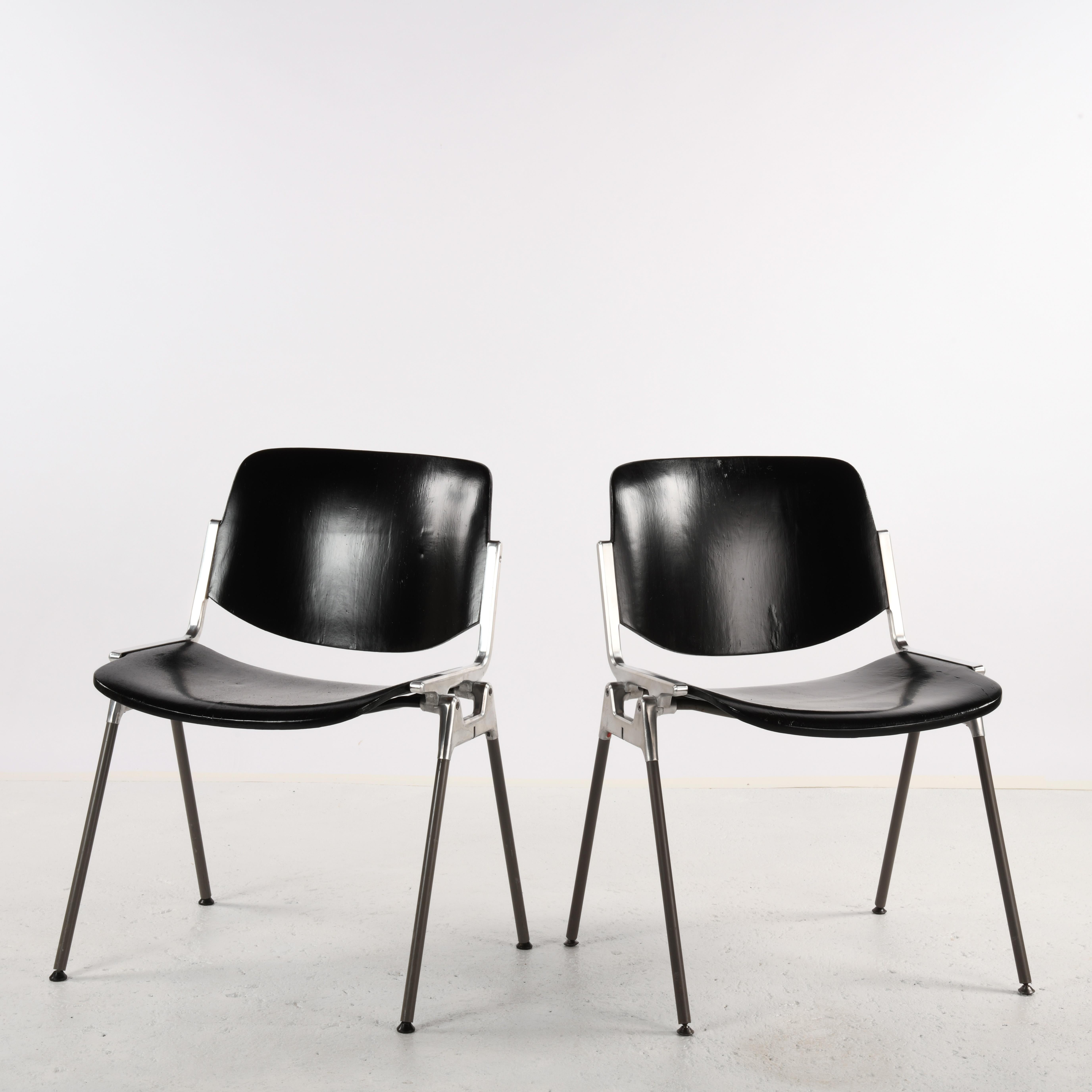 Pareja de sillas modelo DSC 106 diseñadas por Giancarlo Piretti en 1965 publicadas por Castelli. Armazón de aluminio fundido, patas metálicas tapizadas en plástico, asiento y respaldo de madera pintada. El asiento y el respaldo estaban tapizados
