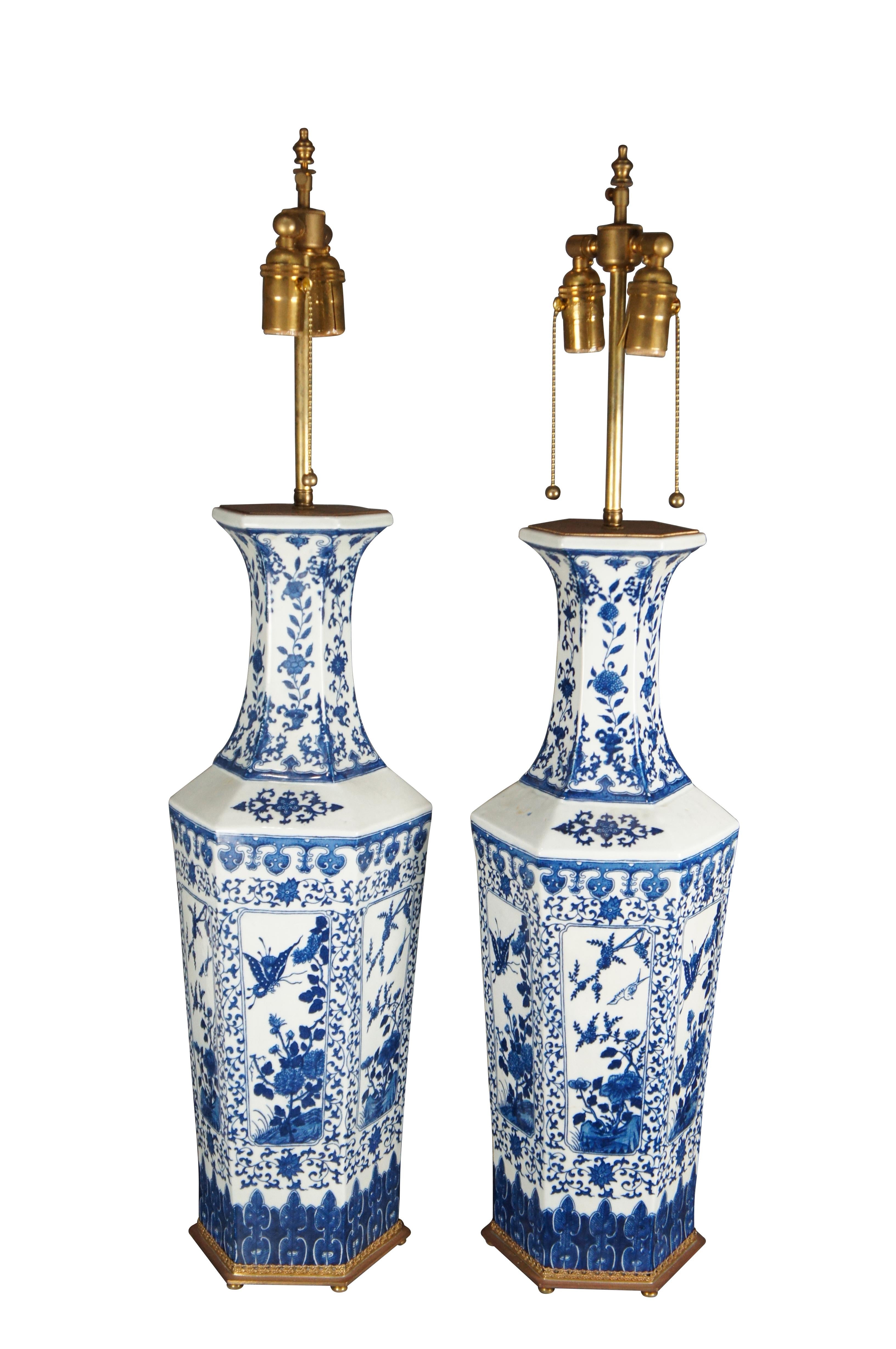 A beautiful pair of Chinese Porcelain Qianlong inspired table lamps. Features a hexagonal form with flared mouth. The vases are white with blue painted nature scenes showcasing an alternating pattern of birds, butterflies and flowers. The foreground